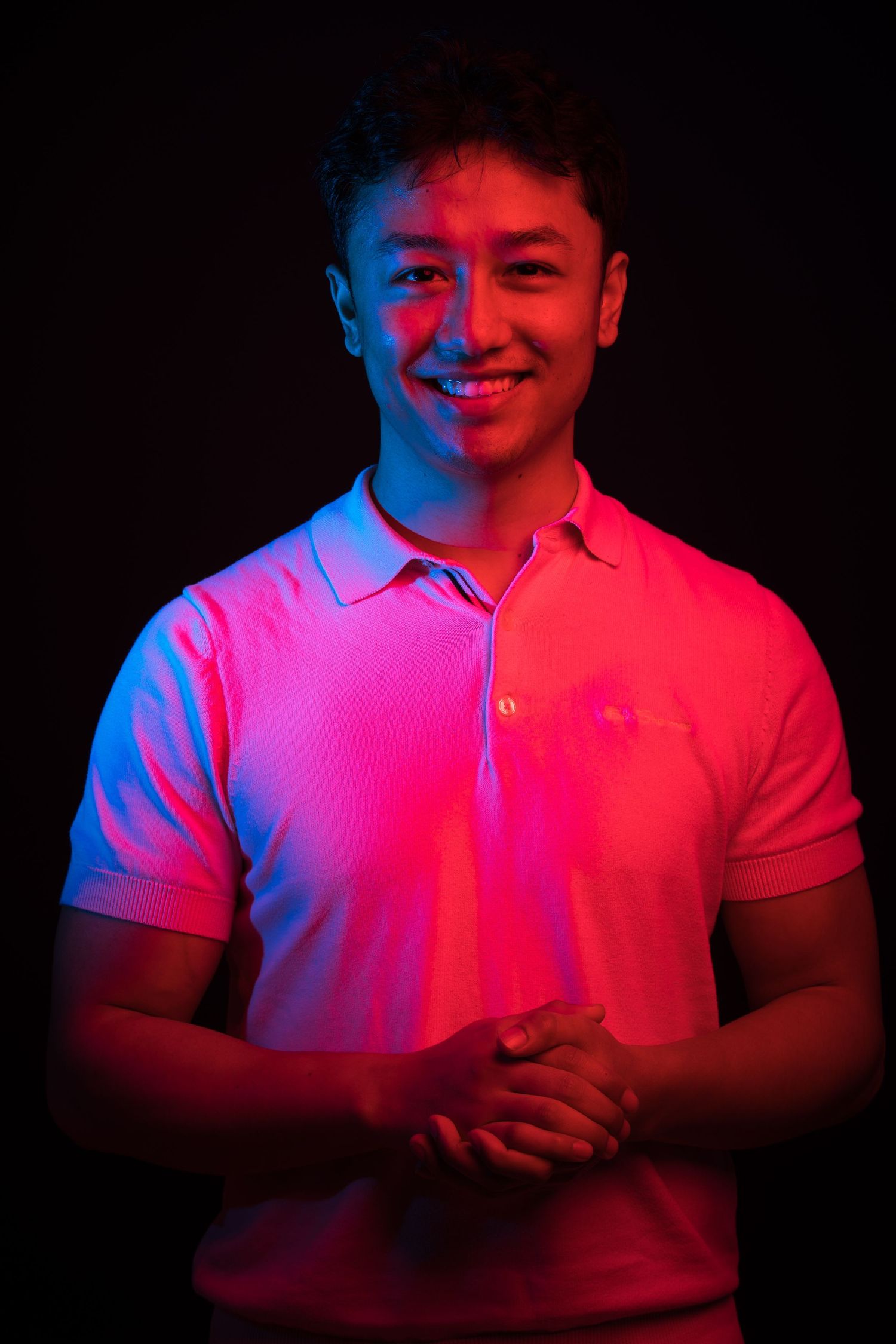 Studio portraits with vibrant pink and blue lighting creating a neon effect on white clothing.