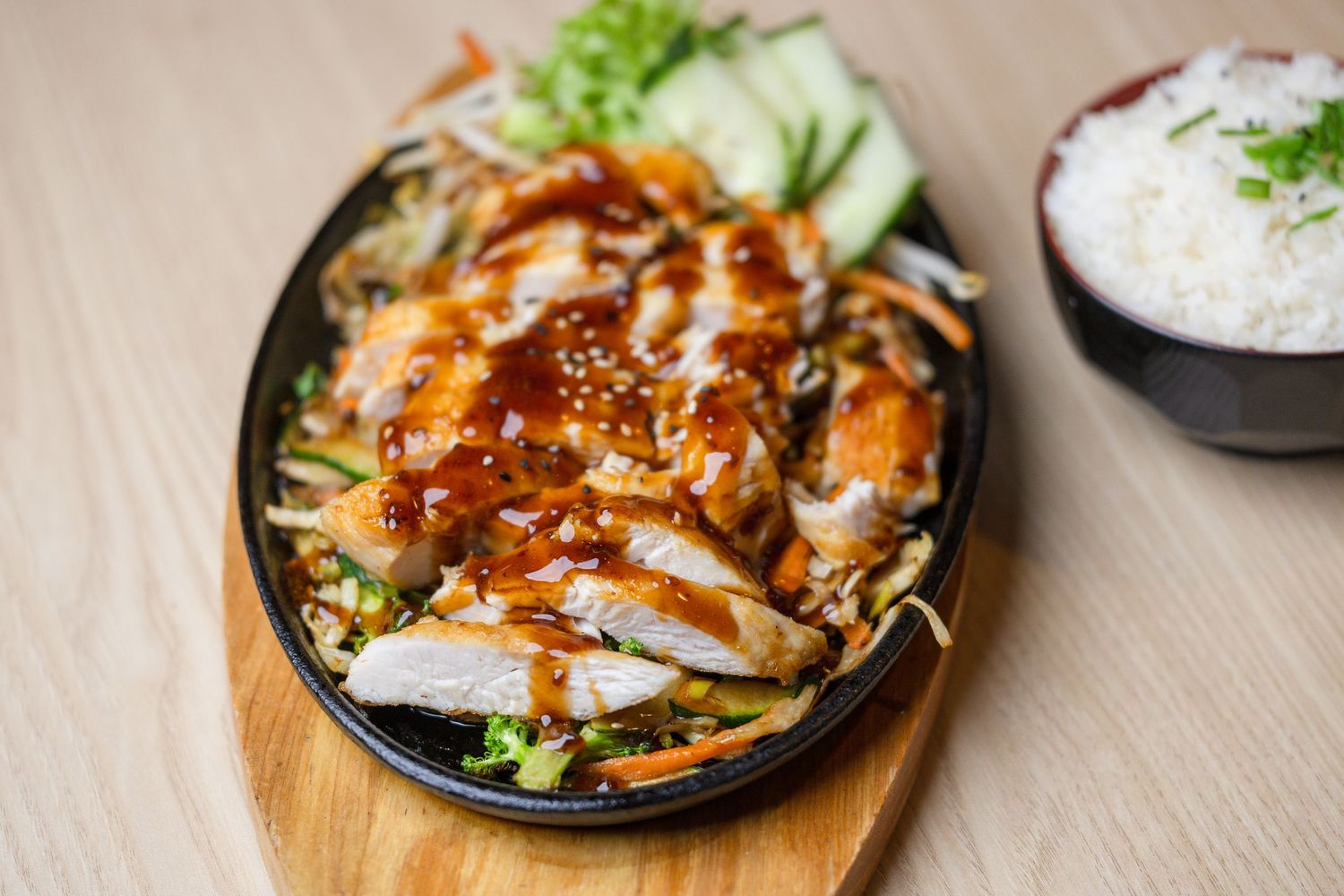 Asian fusion dishes served on dark plates with colorful garnishes and sauces.