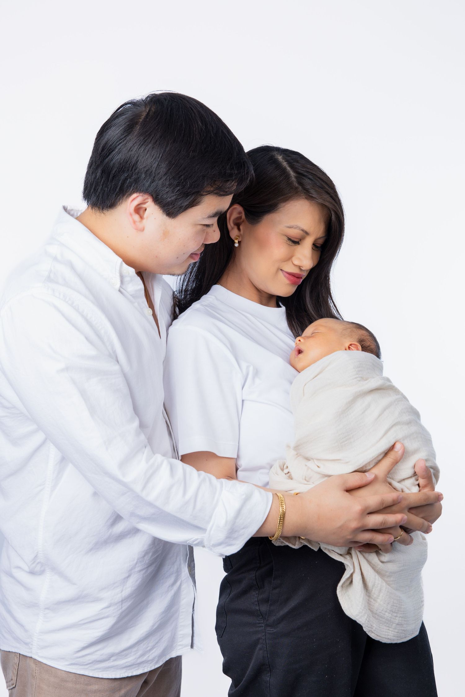 Intimate family moment in white studio setting with gentle embrace.
