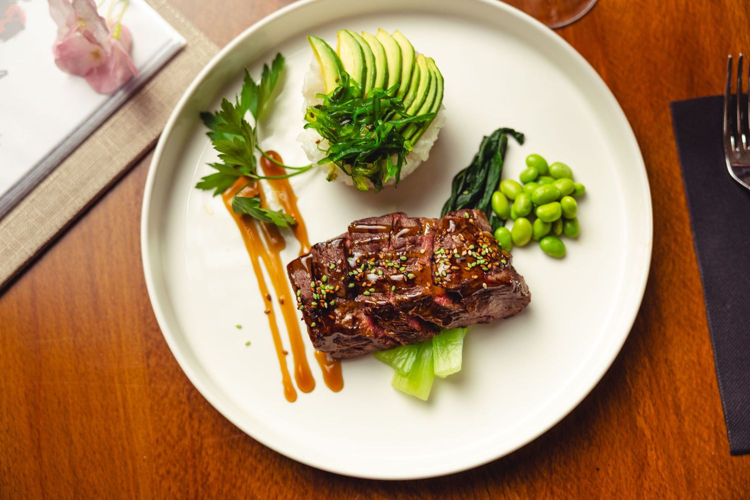 Artistically plated steak dish with vegetables and garnishes on white plates.