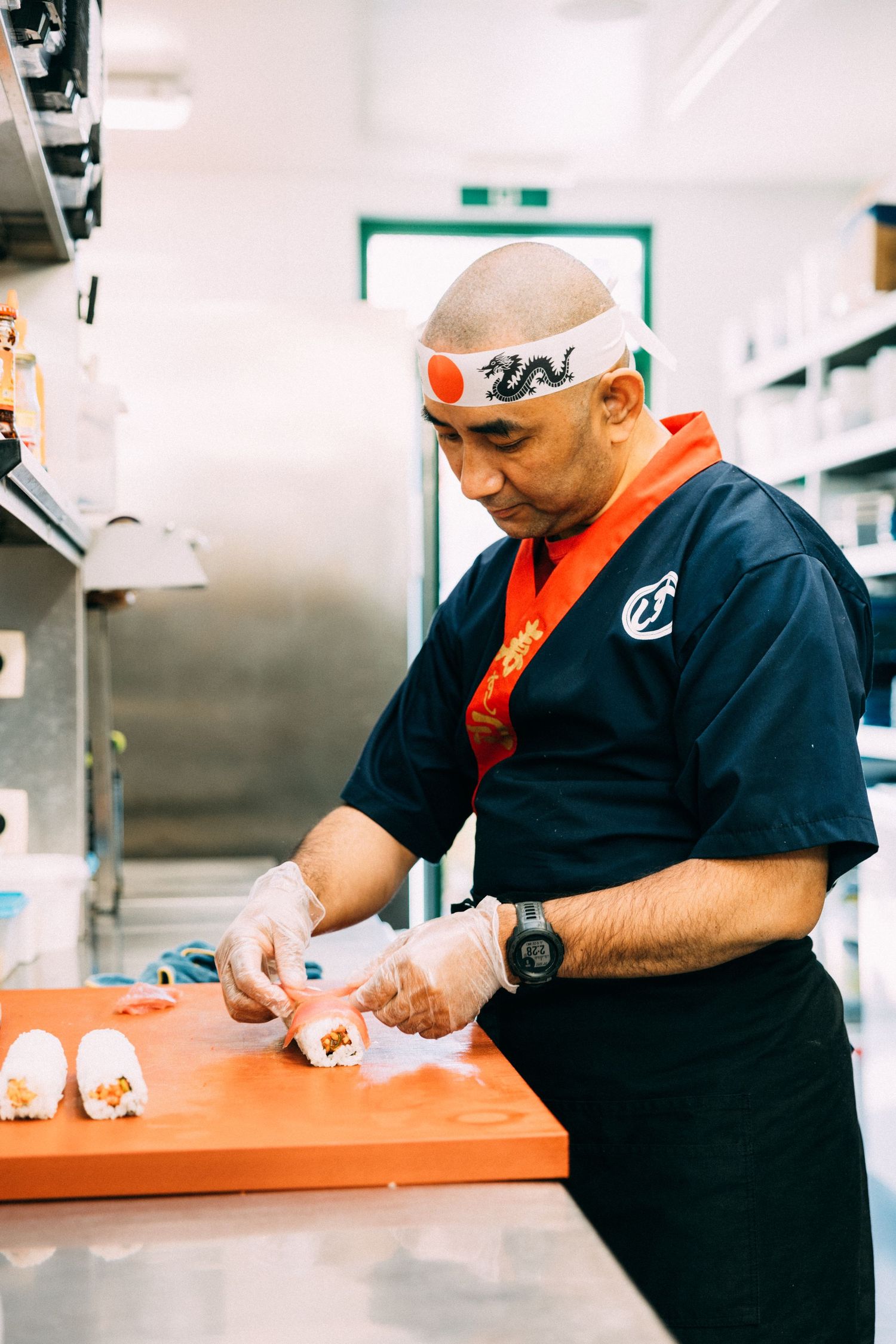 Chef in navy uniform preparing food at wooden cutting board in commercial kitchen.