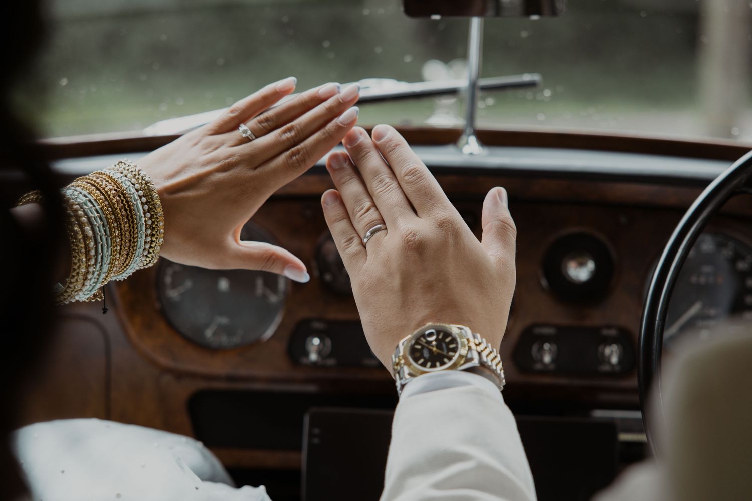 Close-up of hands on a vintage car steering wheel showing ornate details and craftsmanship.