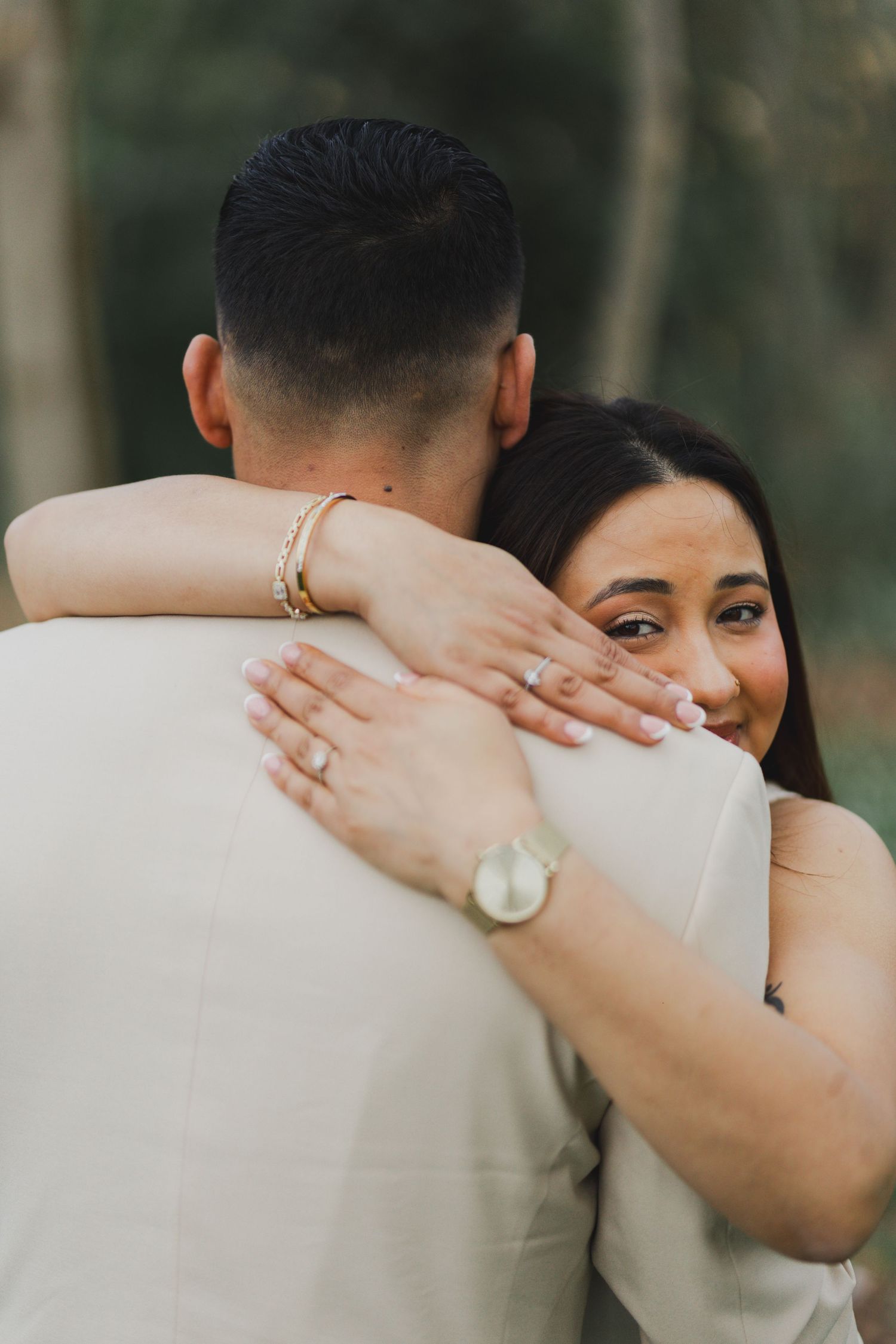 A close embrace showing jewelry and wedding rings during an outdoor photo session.