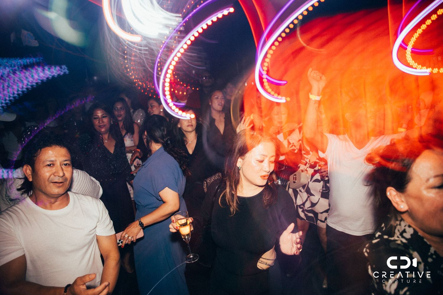 Crowd dancing under colorful neon lights at nightclub event.