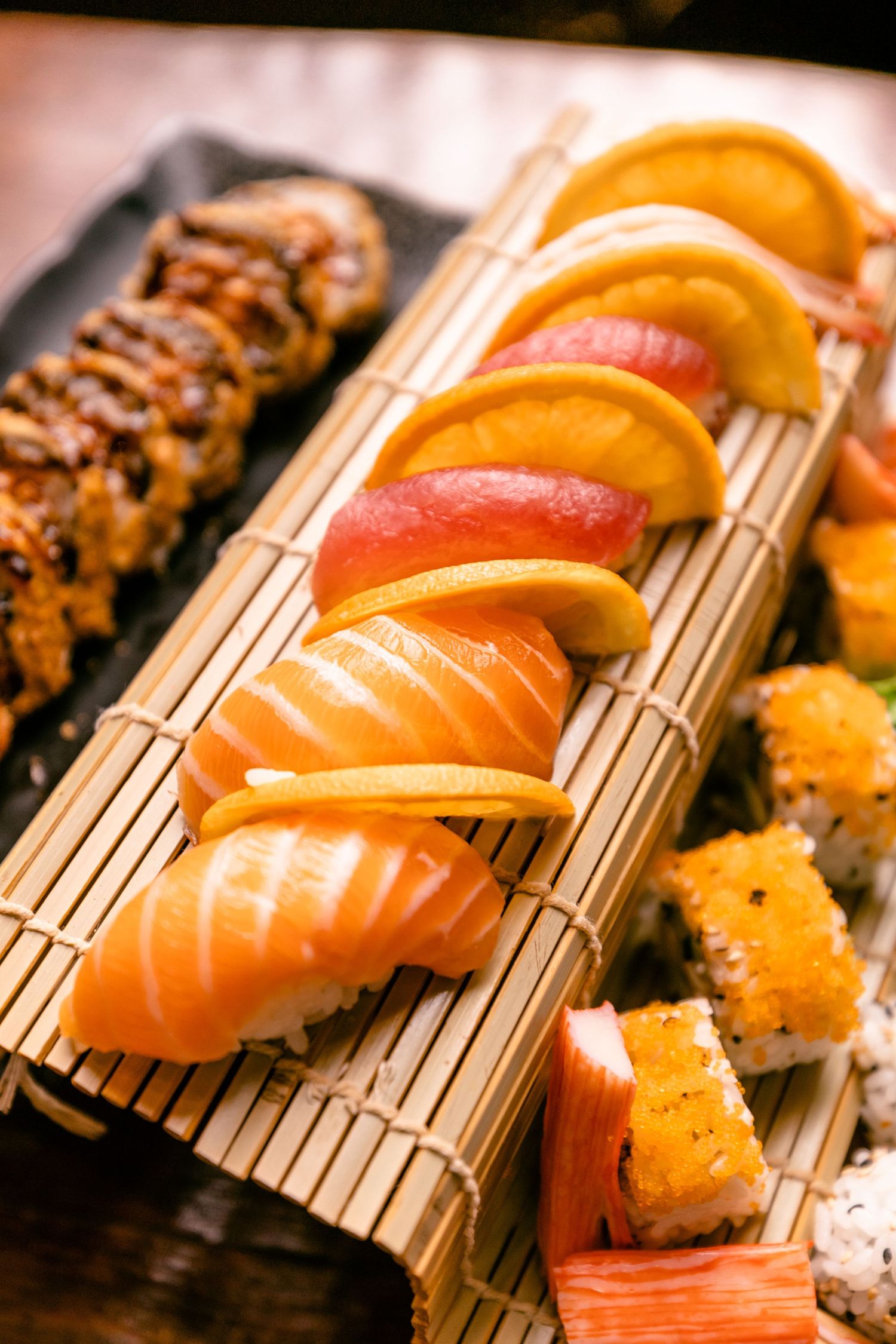 Colorful nigiri sushi pieces arranged on traditional bamboo rolling mats.
