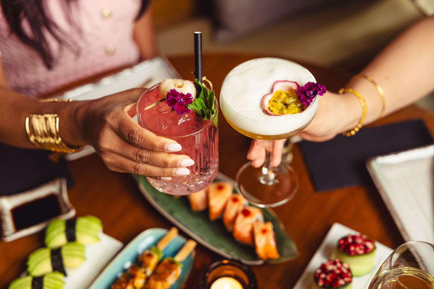 Close-up shot of hands holding wine glasses in a dimly lit restaurant setting.