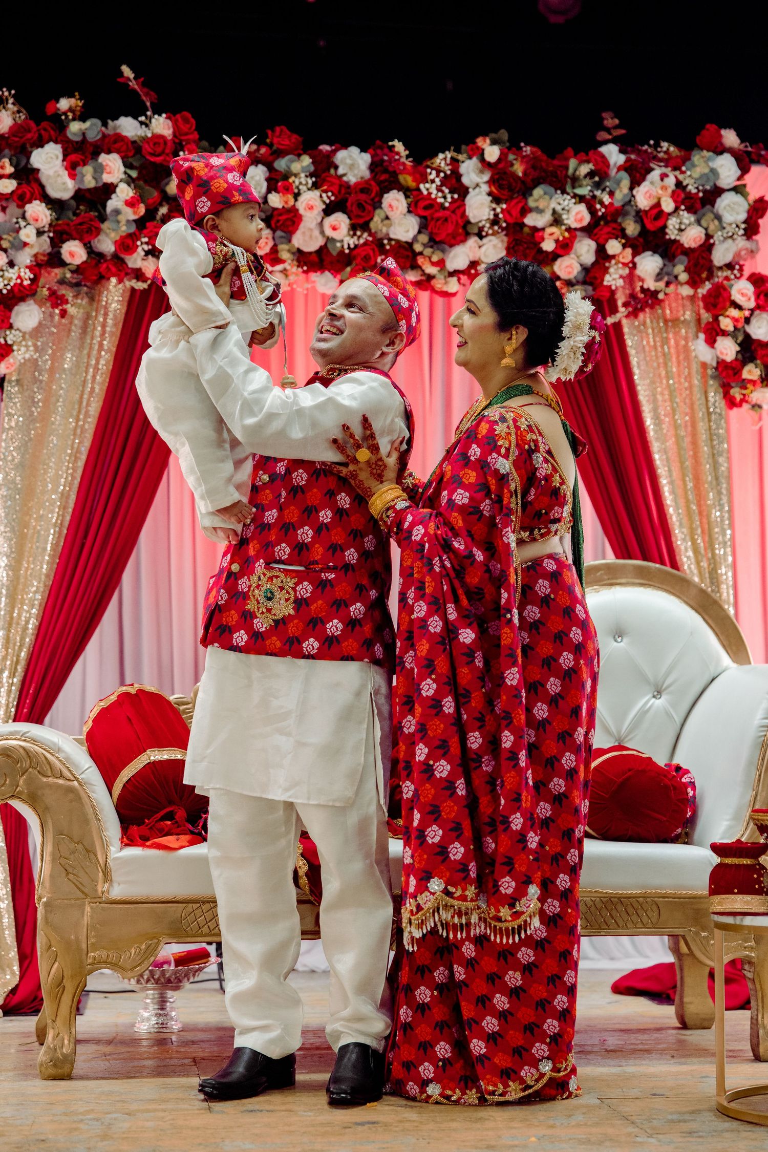 Cultural celebration with ornate red and white floral decorations and traditional attire.