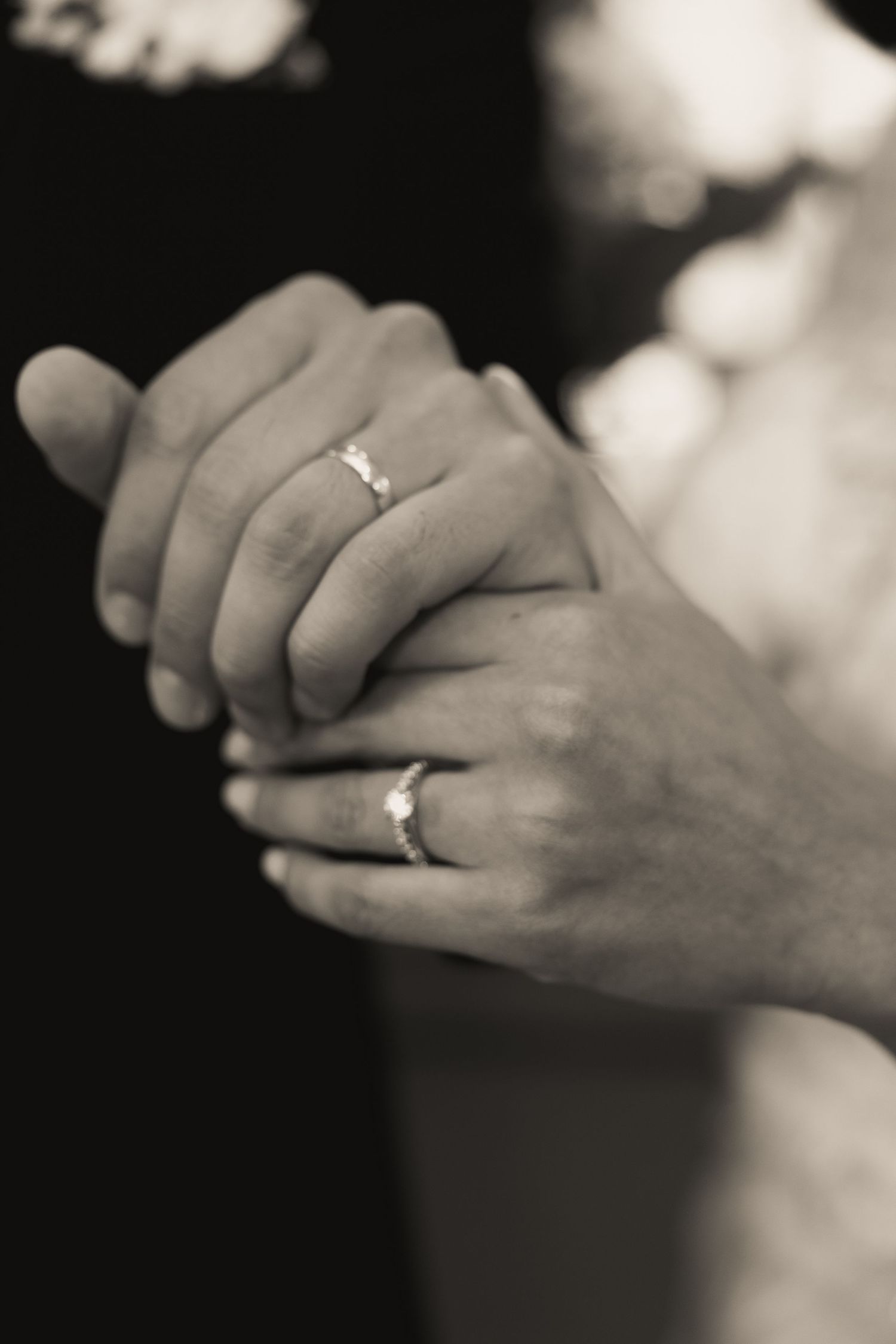 Black and white close-up series of hands with wedding rings showing tender moments.