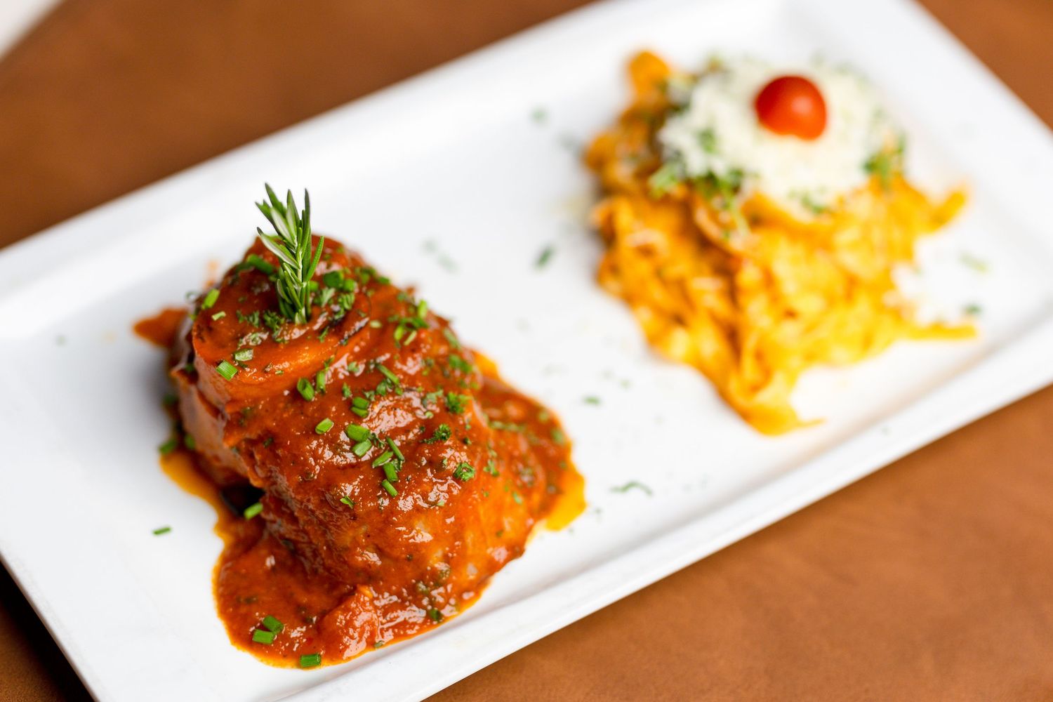 Selection of colorful cooked dishes plated on long white rectangular plates.