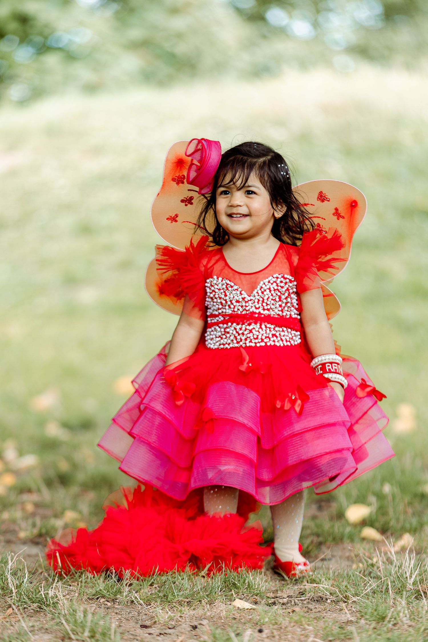 Red and pink tulle party dress photographed outdoors in natural setting.