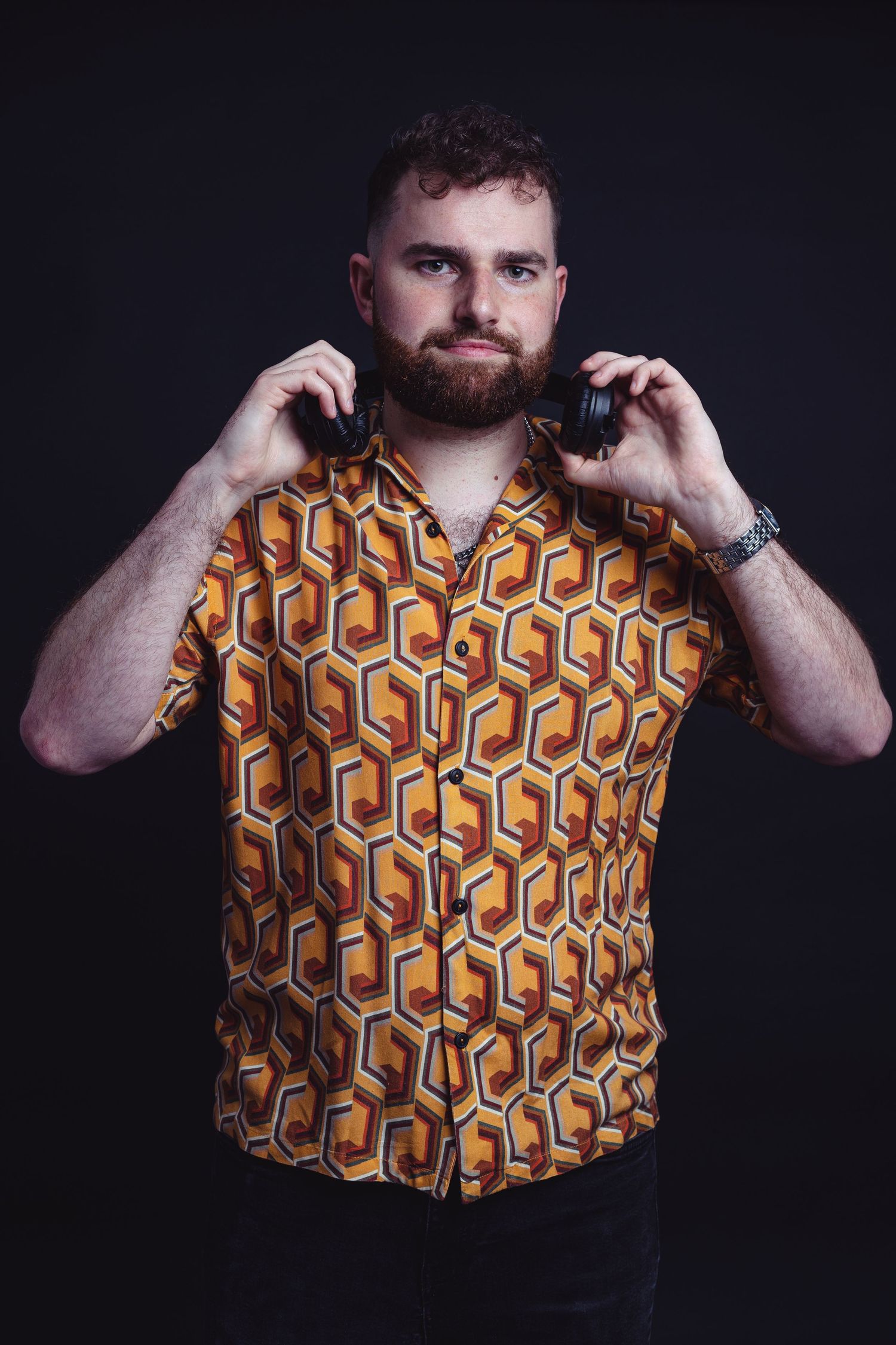 Person modeling retro-style geometric pattern shirt in dramatic studio lighting.