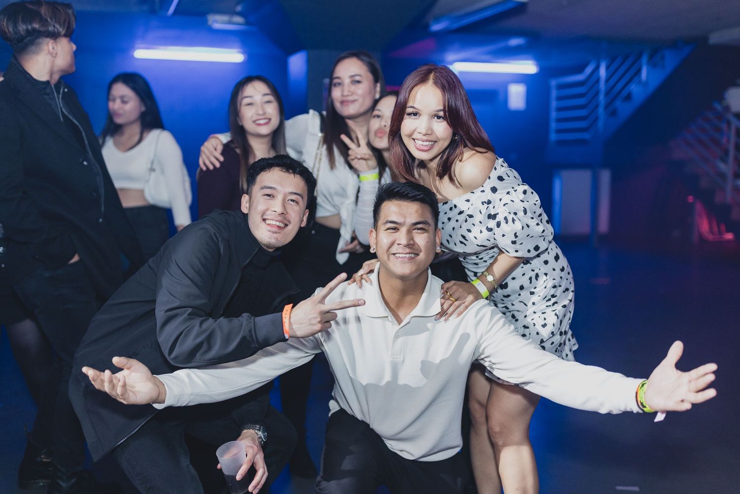 Group of friends posing and having fun at a nightclub with blue lighting.