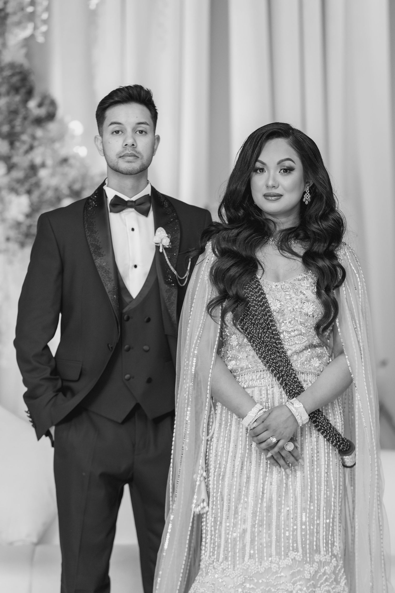 Elegant couple in formal black tie and sparkling white gown pose at their wedding reception.