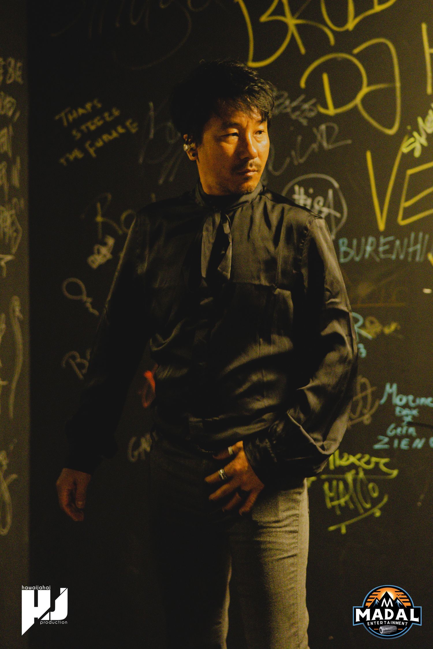 Dramatic portrait against graffiti wall with moody lighting creating artistic atmosphere.