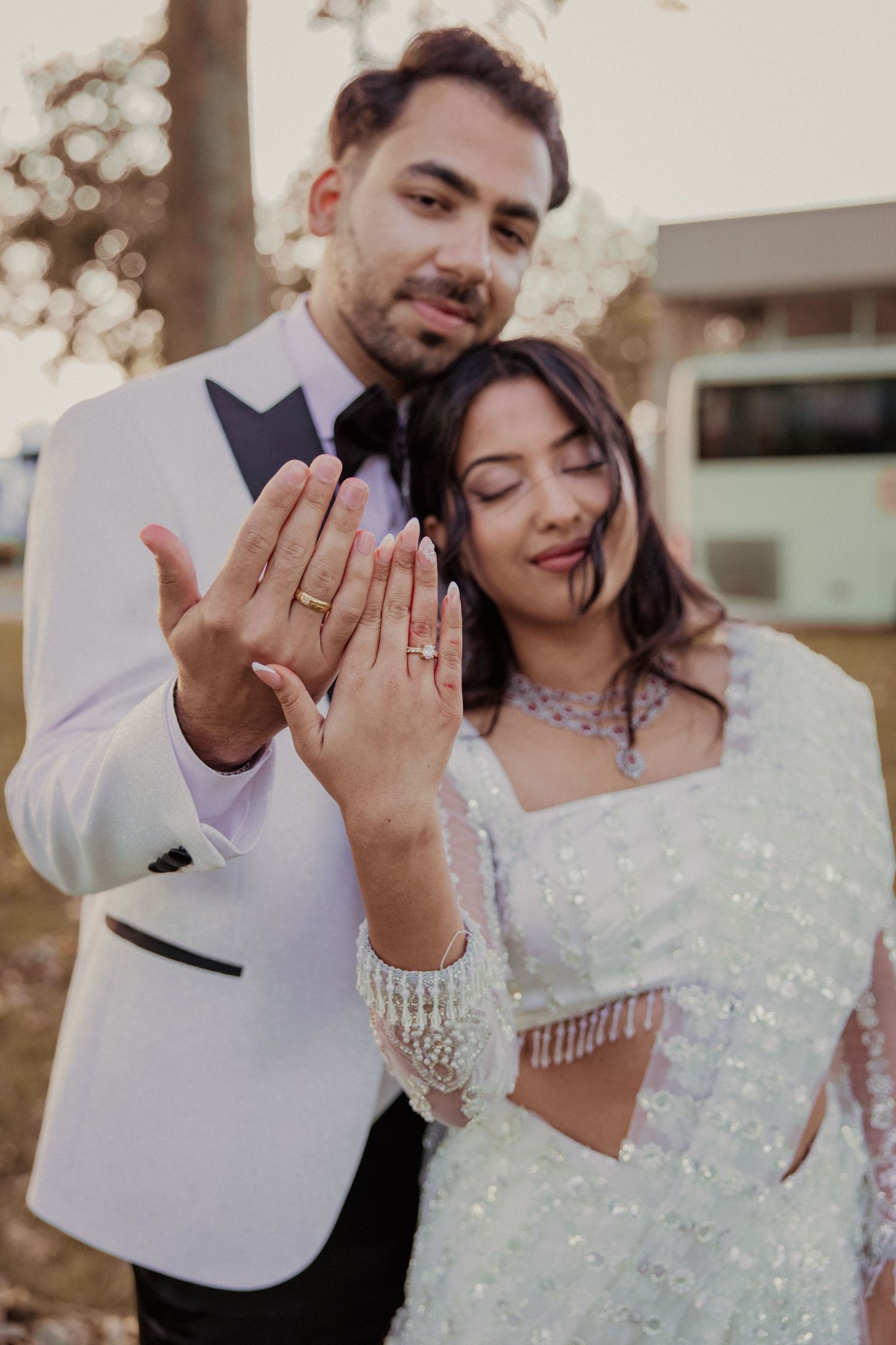 Close-up shots of couple showing off wedding rings against sparkly backdrop.