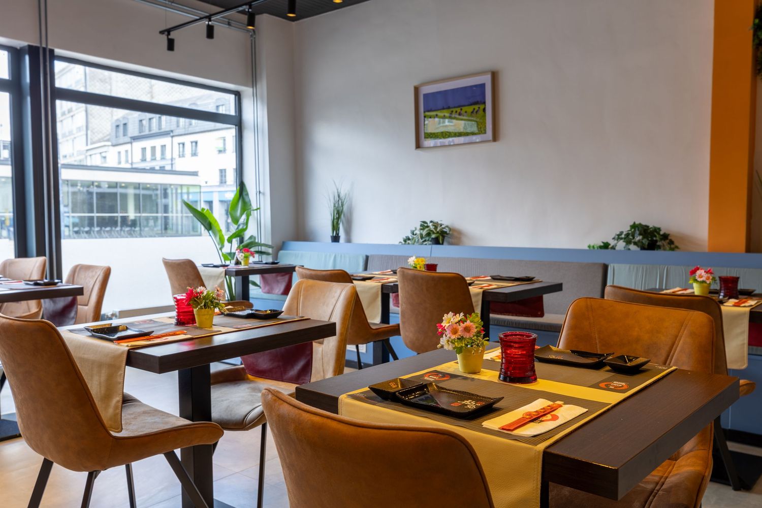 Modern restaurant interior with comfortable seating and large windows providing natural light.