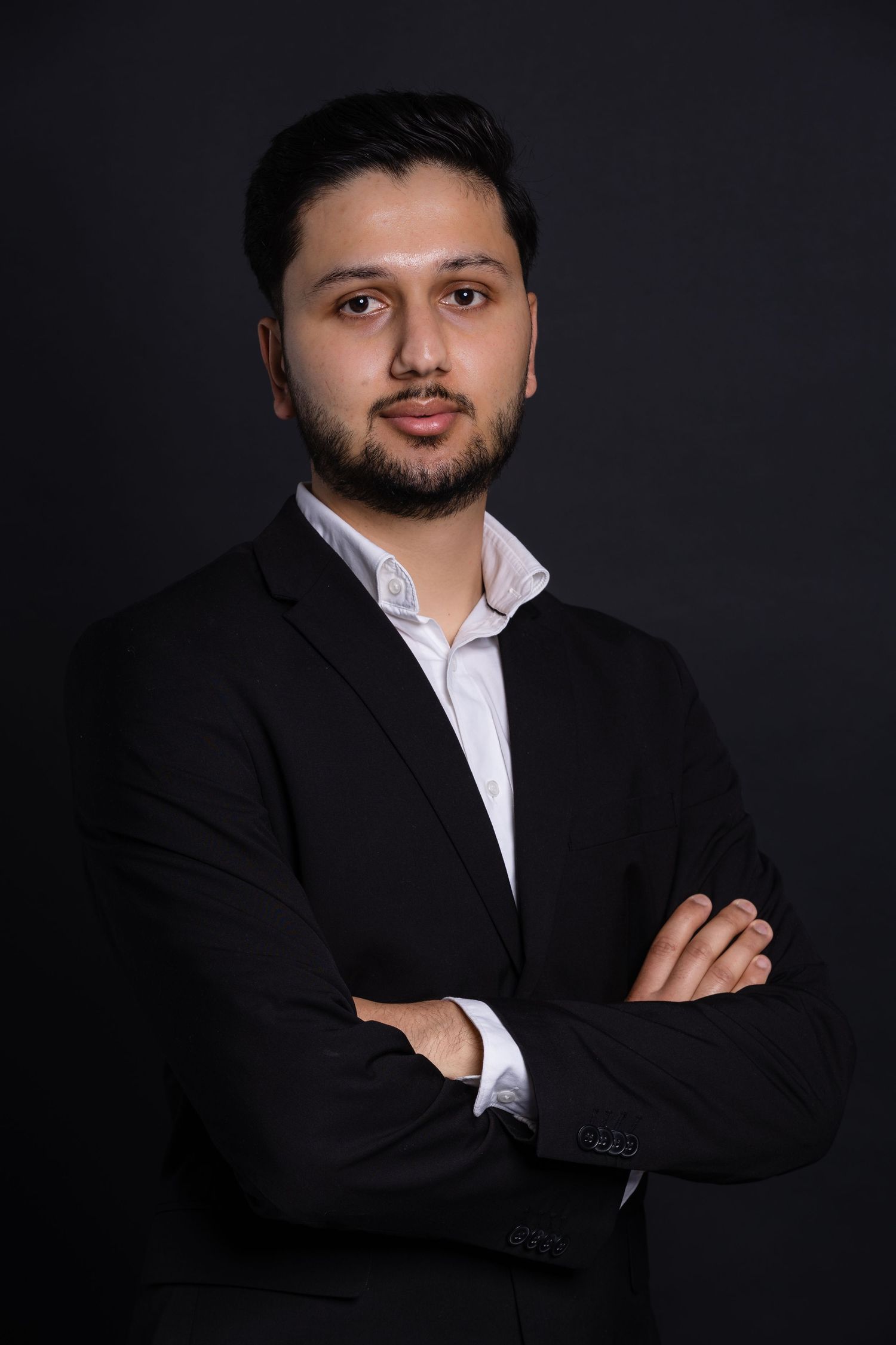 Professional headshots of a person in formal black suit and white shirt against dark backdrop.