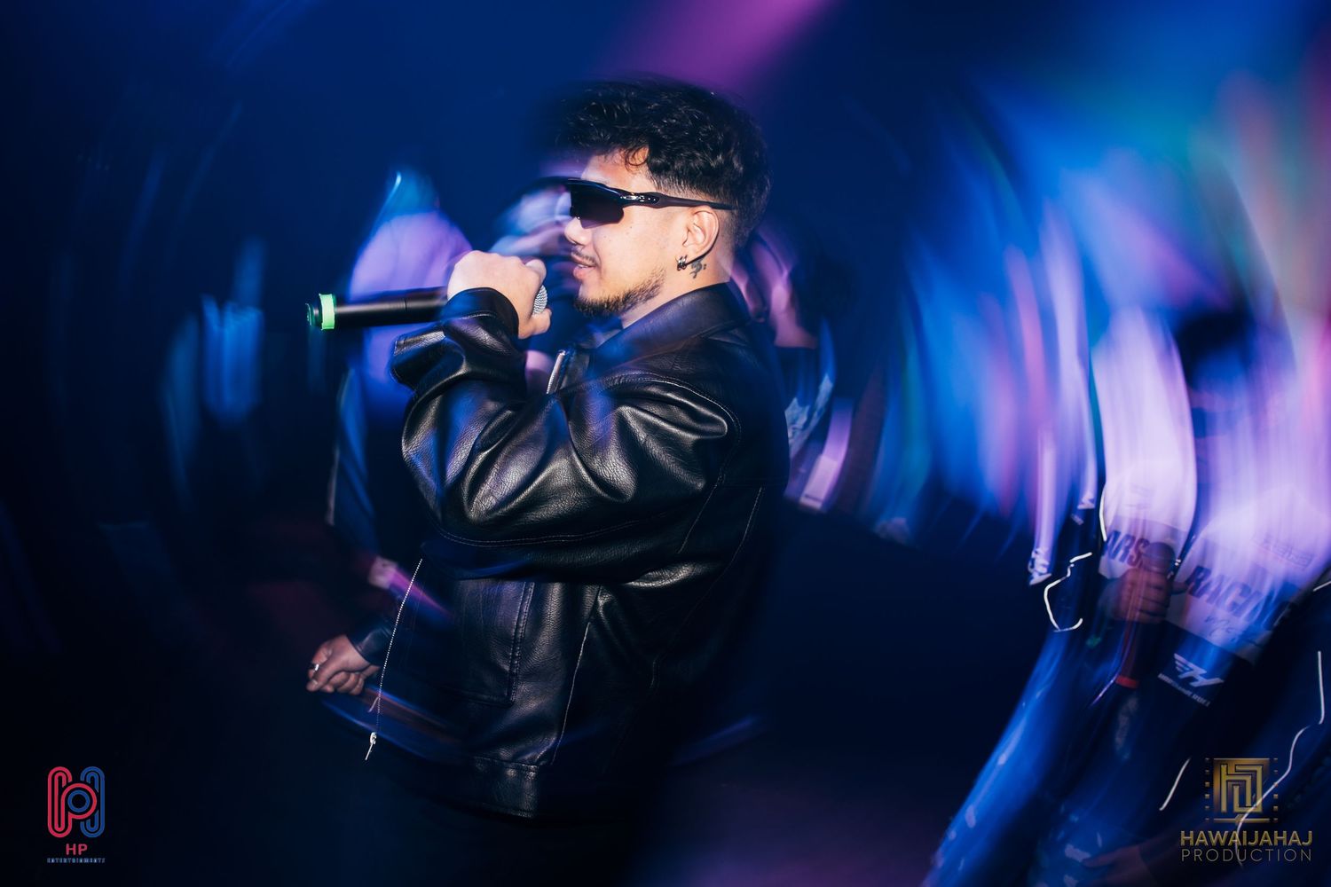 Performance in leather jacket with dramatic blue and purple stage lighting effects.