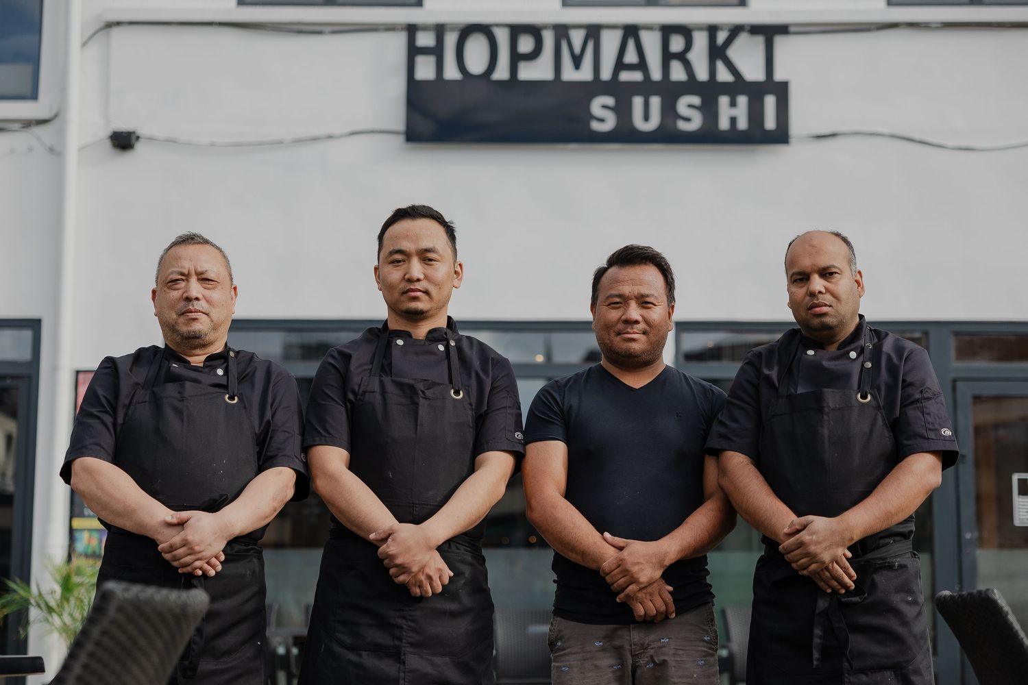 Exterior view of a sushi restaurant with Hopmarkt signage and staff lined up outside.