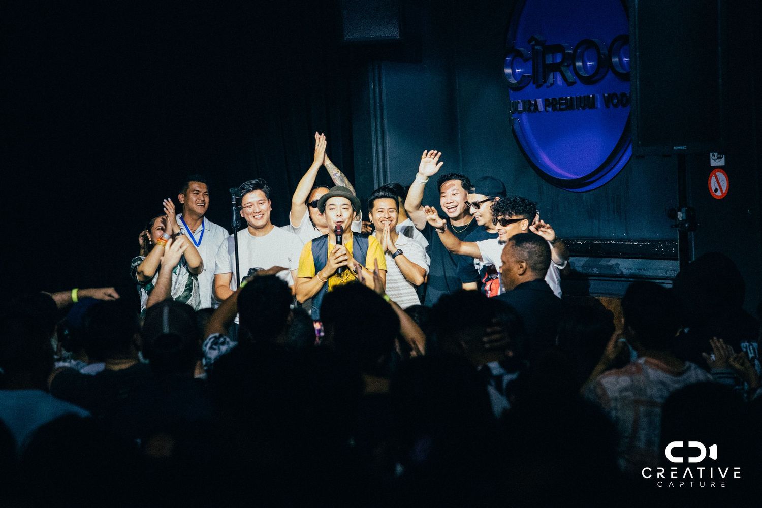 Band members celebrating with raised arms during concert finale.