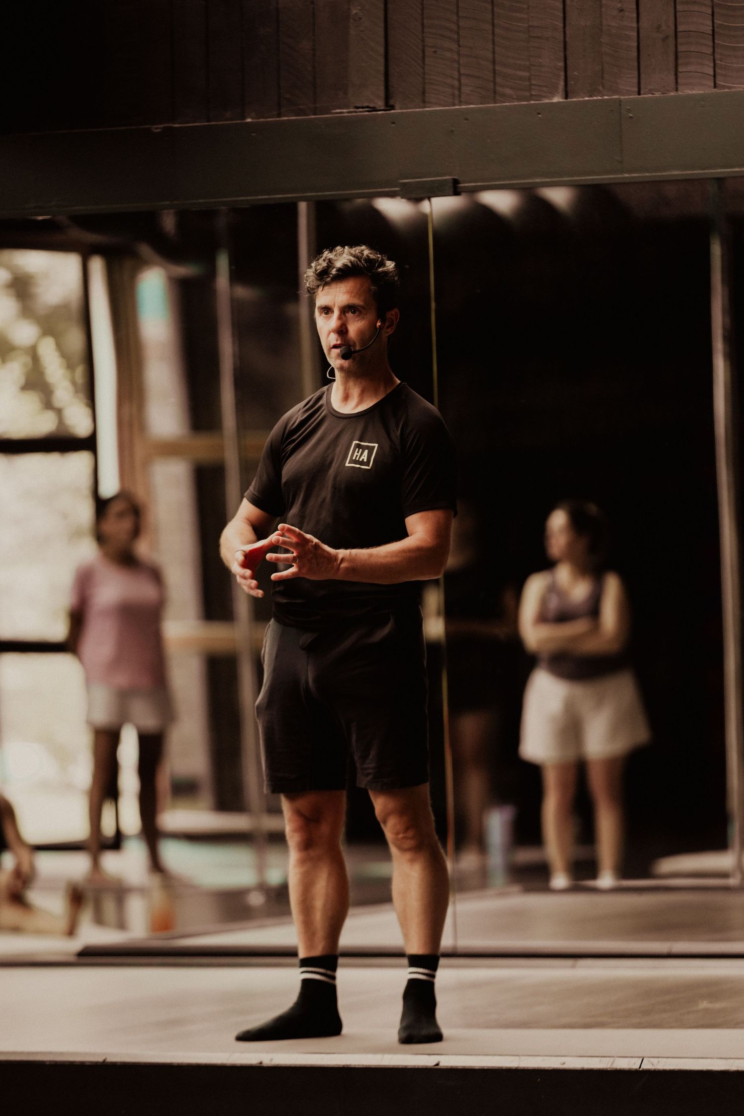 Person in black athletic wear checking their phone while standing in a modern gym space.