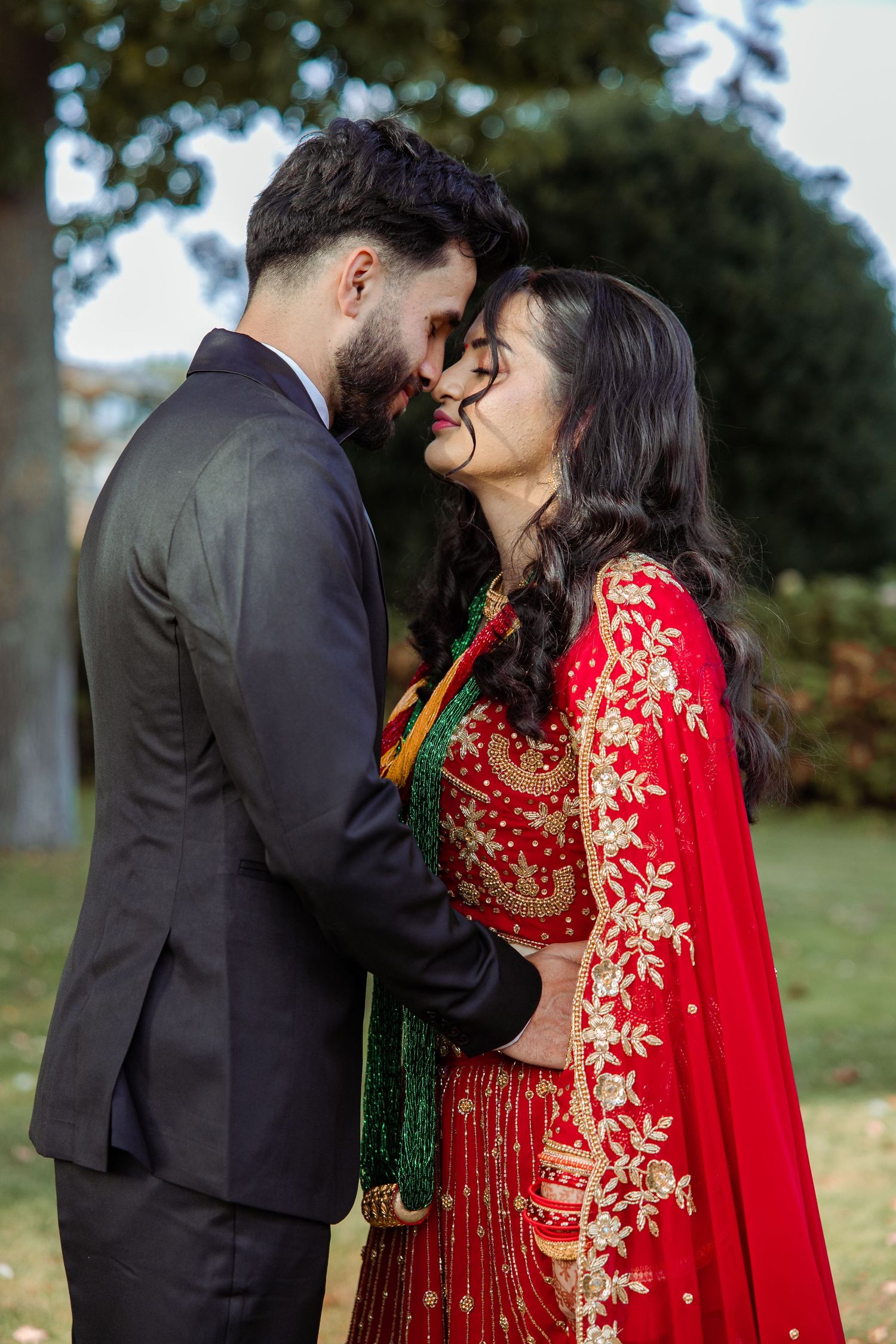 Romantic couple in formal attire sharing intimate moments in an outdoor garden setting.