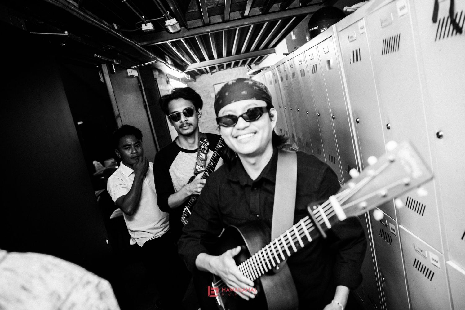 Musicians with guitar posing backstage in black and white photography.