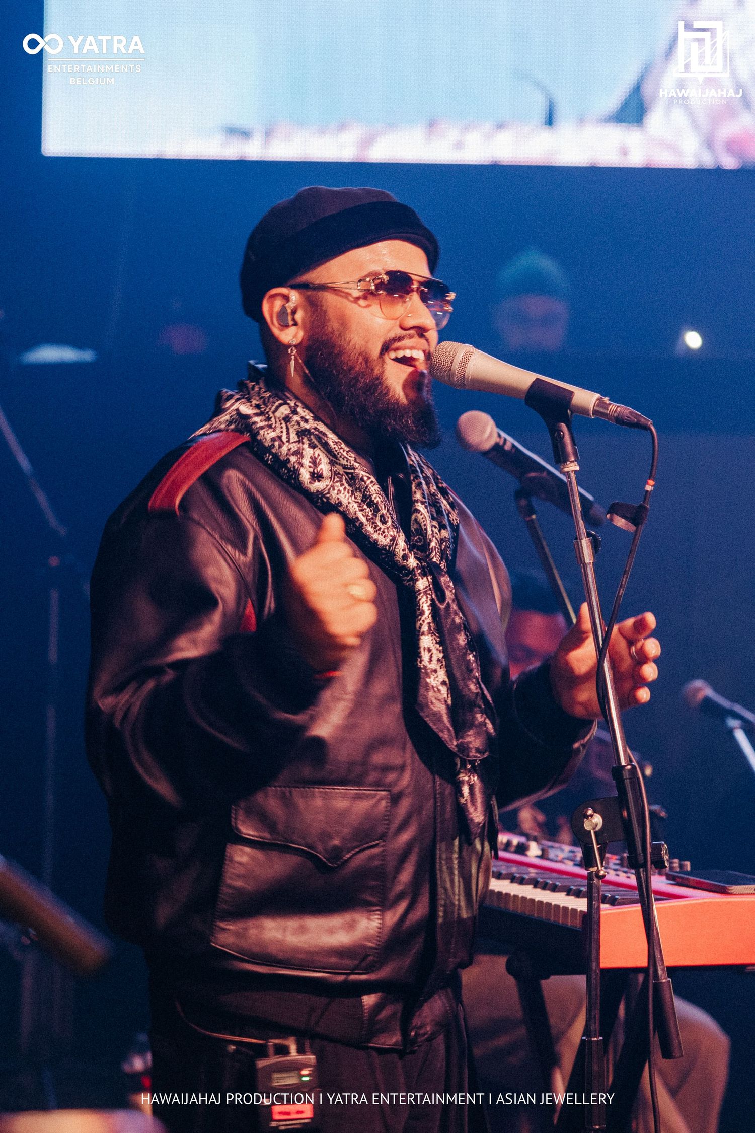 Musician performs with microphone on stage bathed in blue concert lighting.