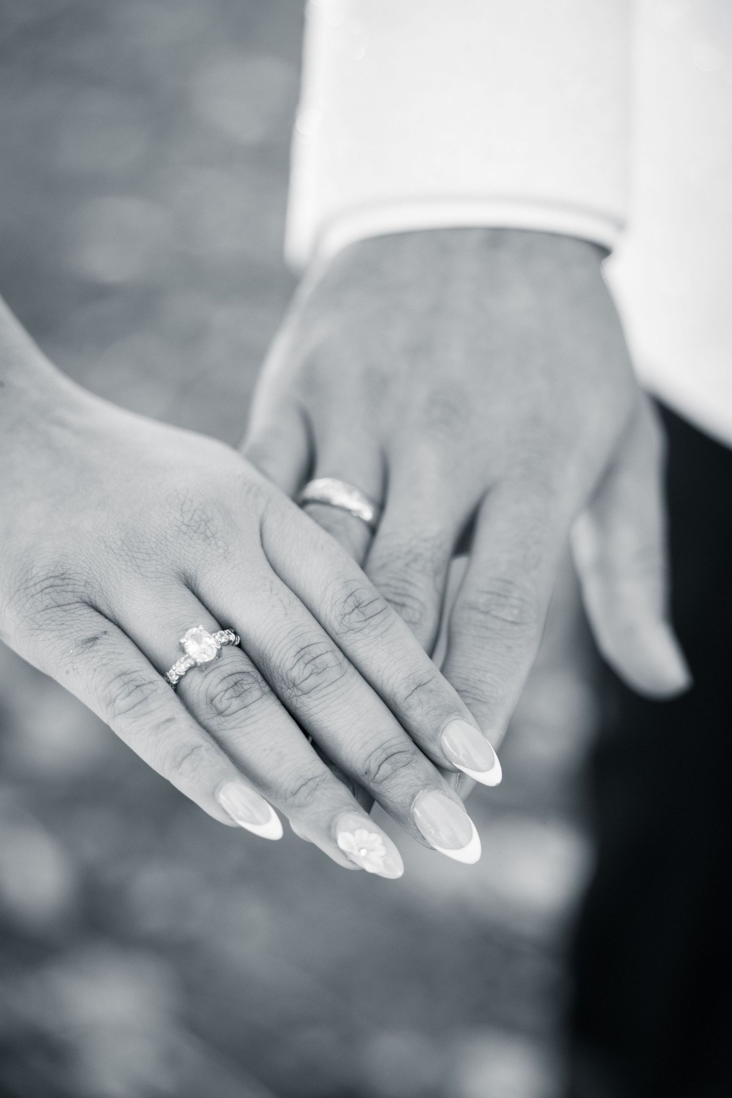 Close up of wedding rings and manicured hands in an artistic black and white photograph.