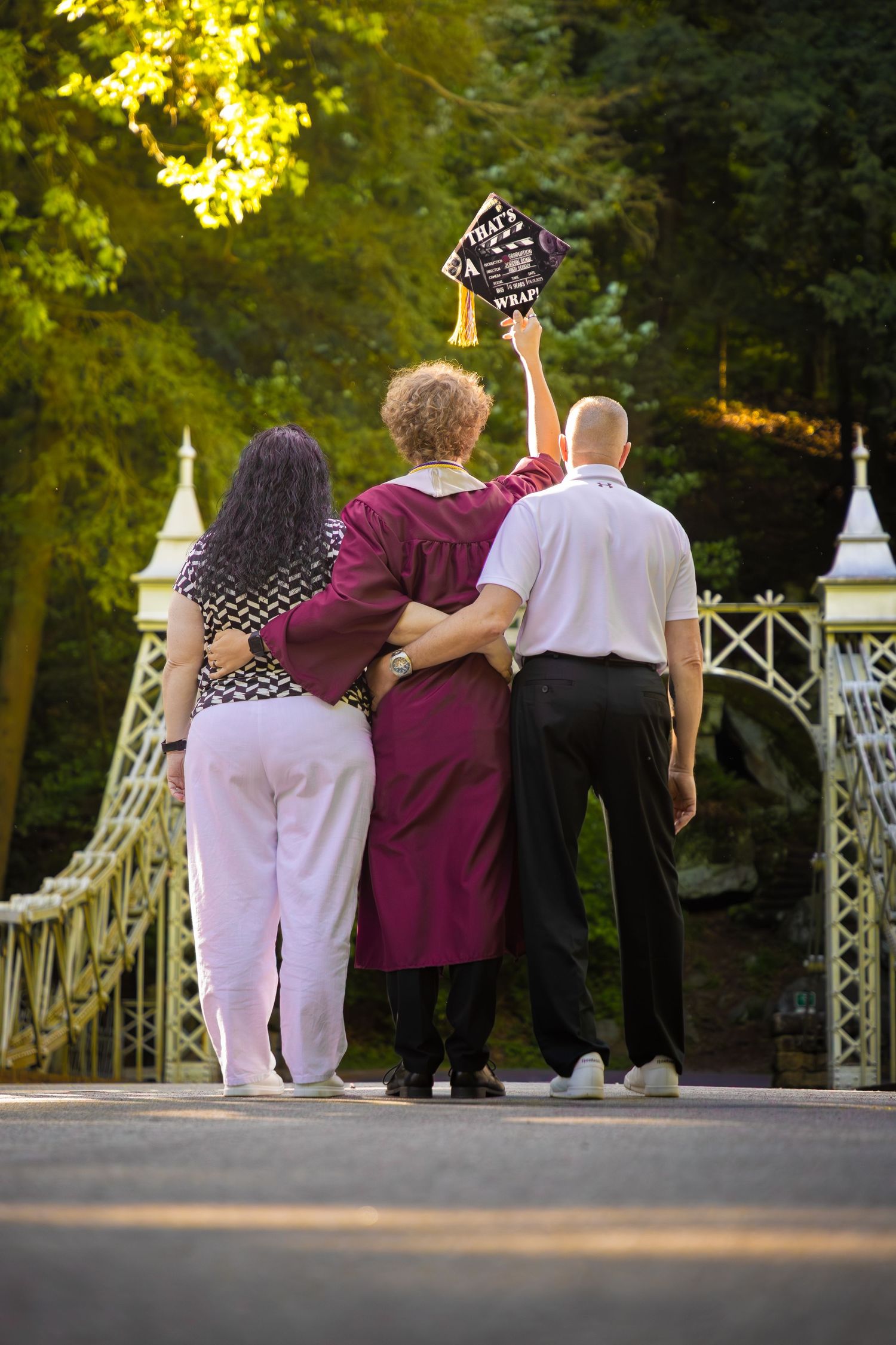 Group poses together on white bridge during graduation celebration.