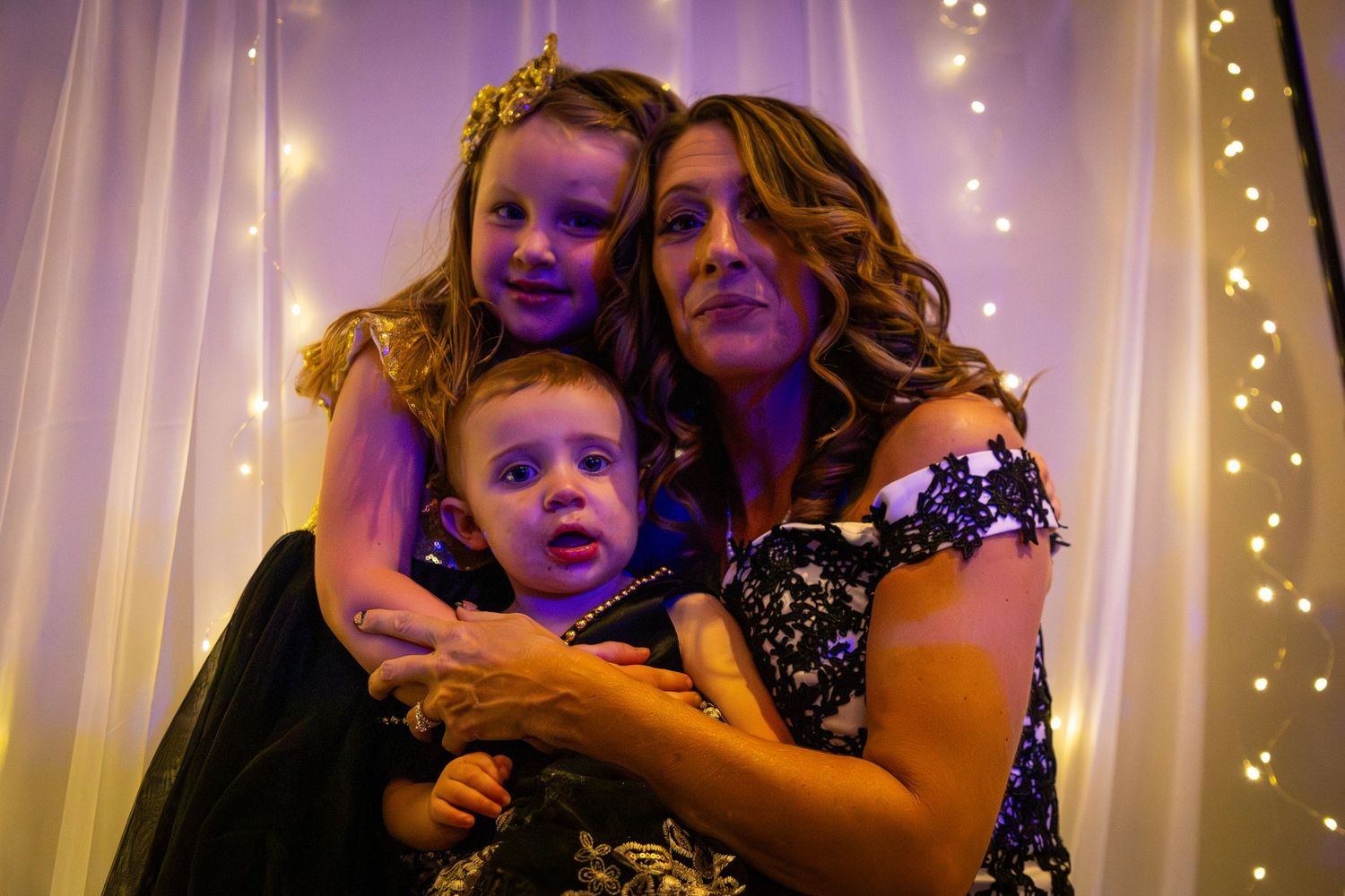 Intimate moment captured in purple-tinted lighting at wedding celebration.