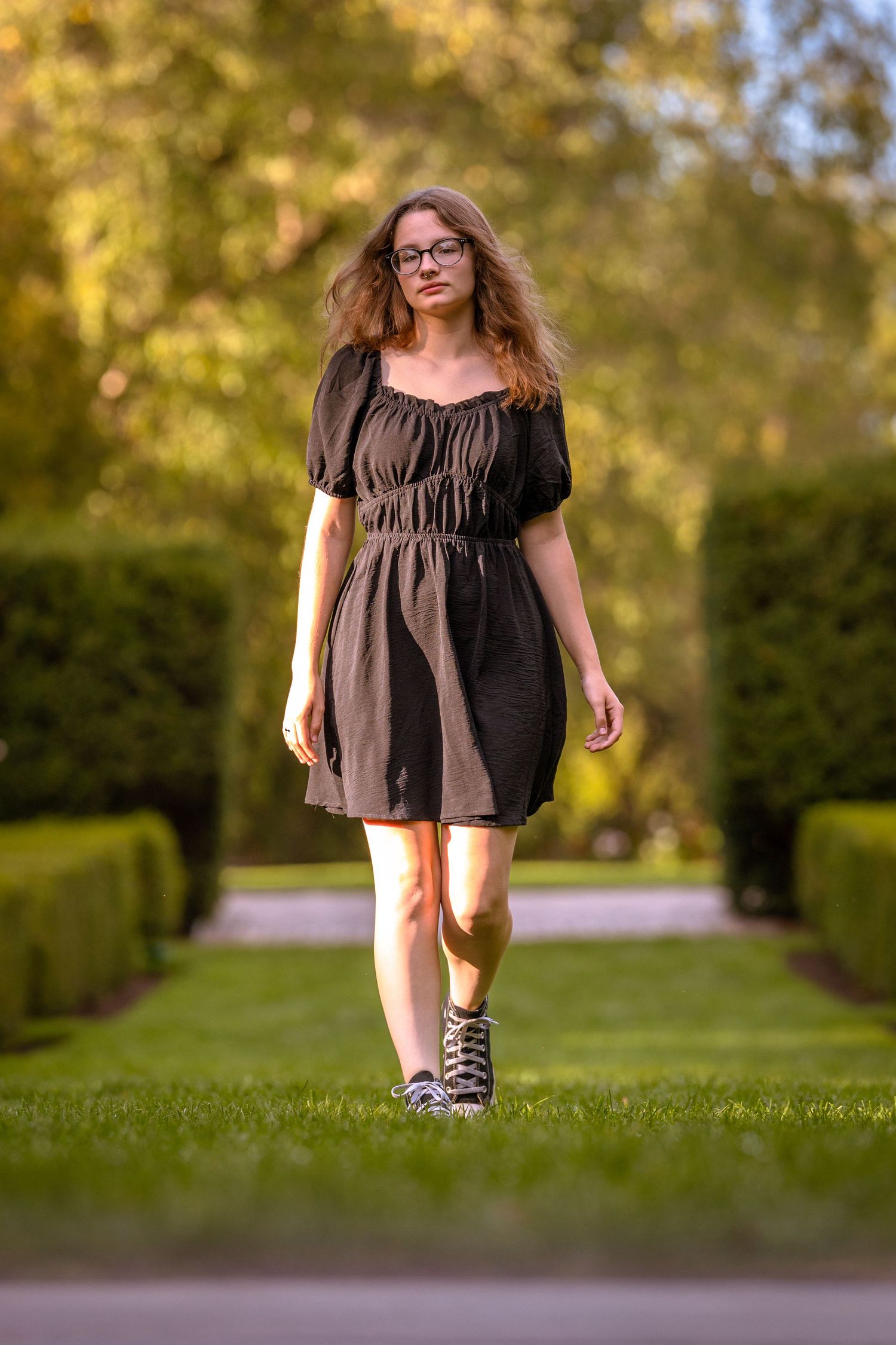 Figure in black dress photographed in dynamic poses on garden path.