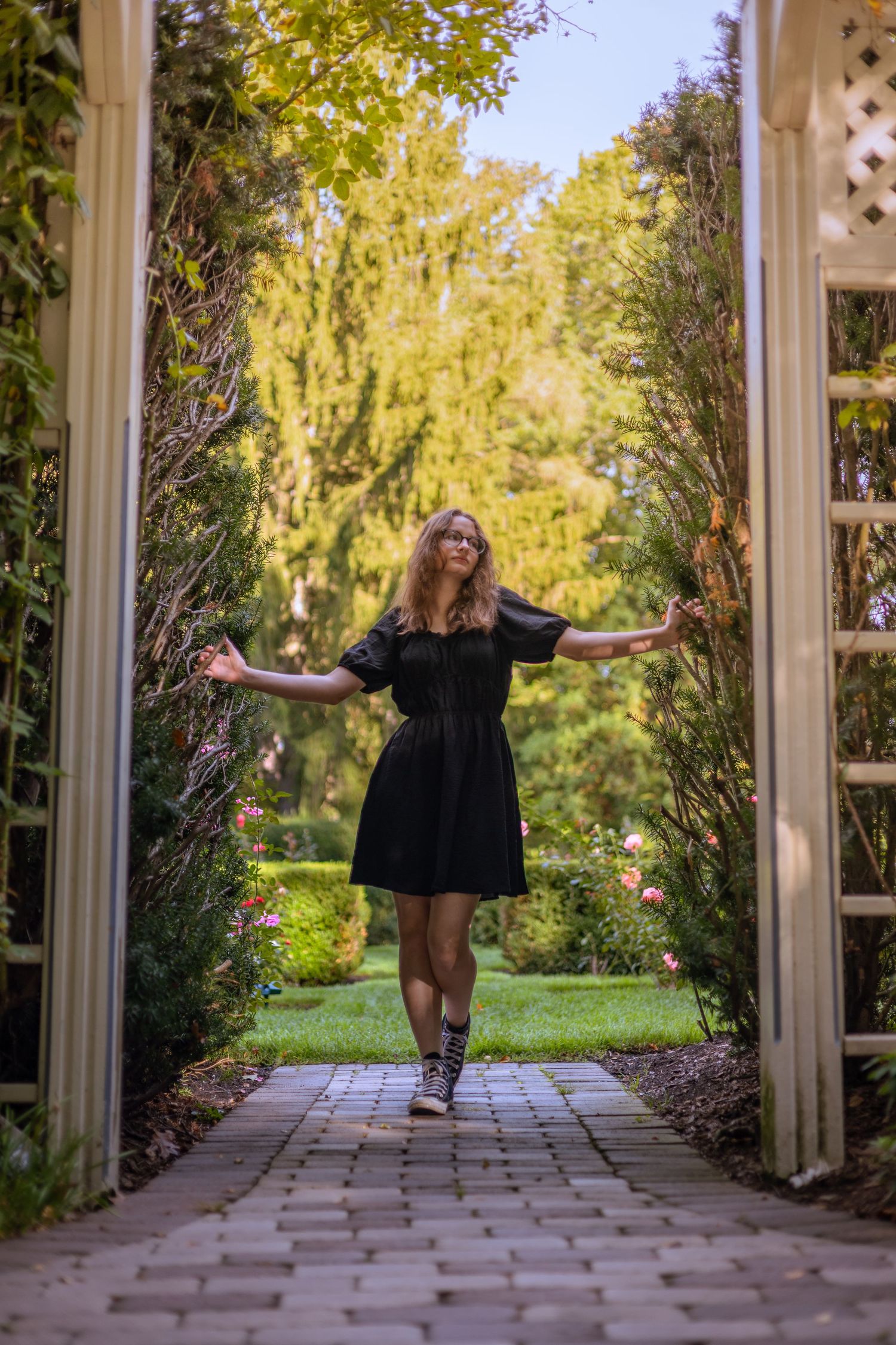 Expressive dance movements captured in a garden walkway with autumn foliage.