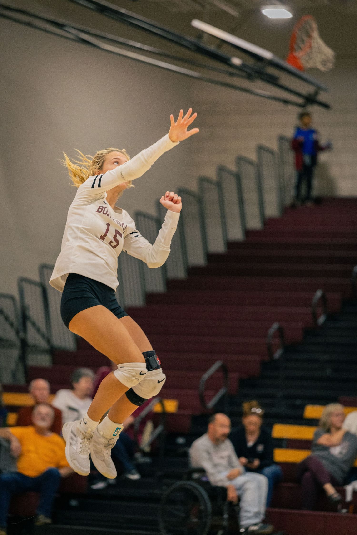 Volleyball player jumping to hit ball during indoor game.