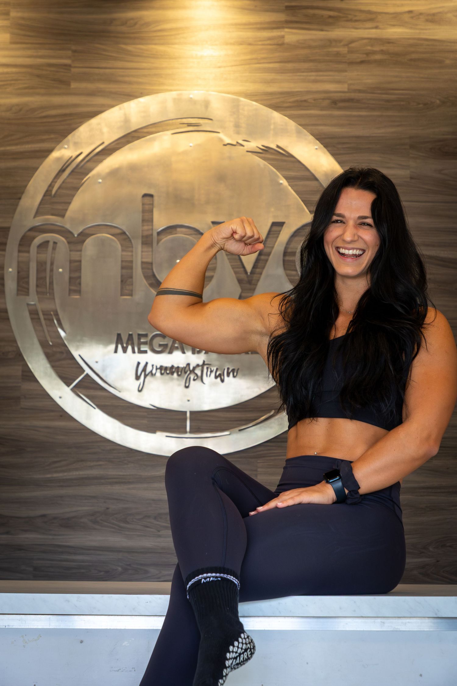 Fitness instructors showing enthusiasm while posing in front of a branded wall display.