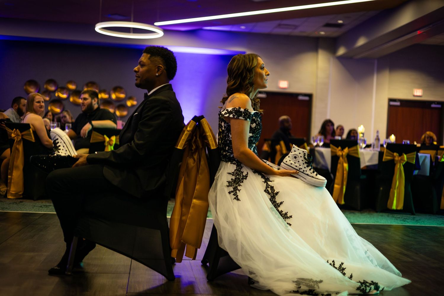 Wedding reception dance floor with guests celebrating under purple ambient lighting.