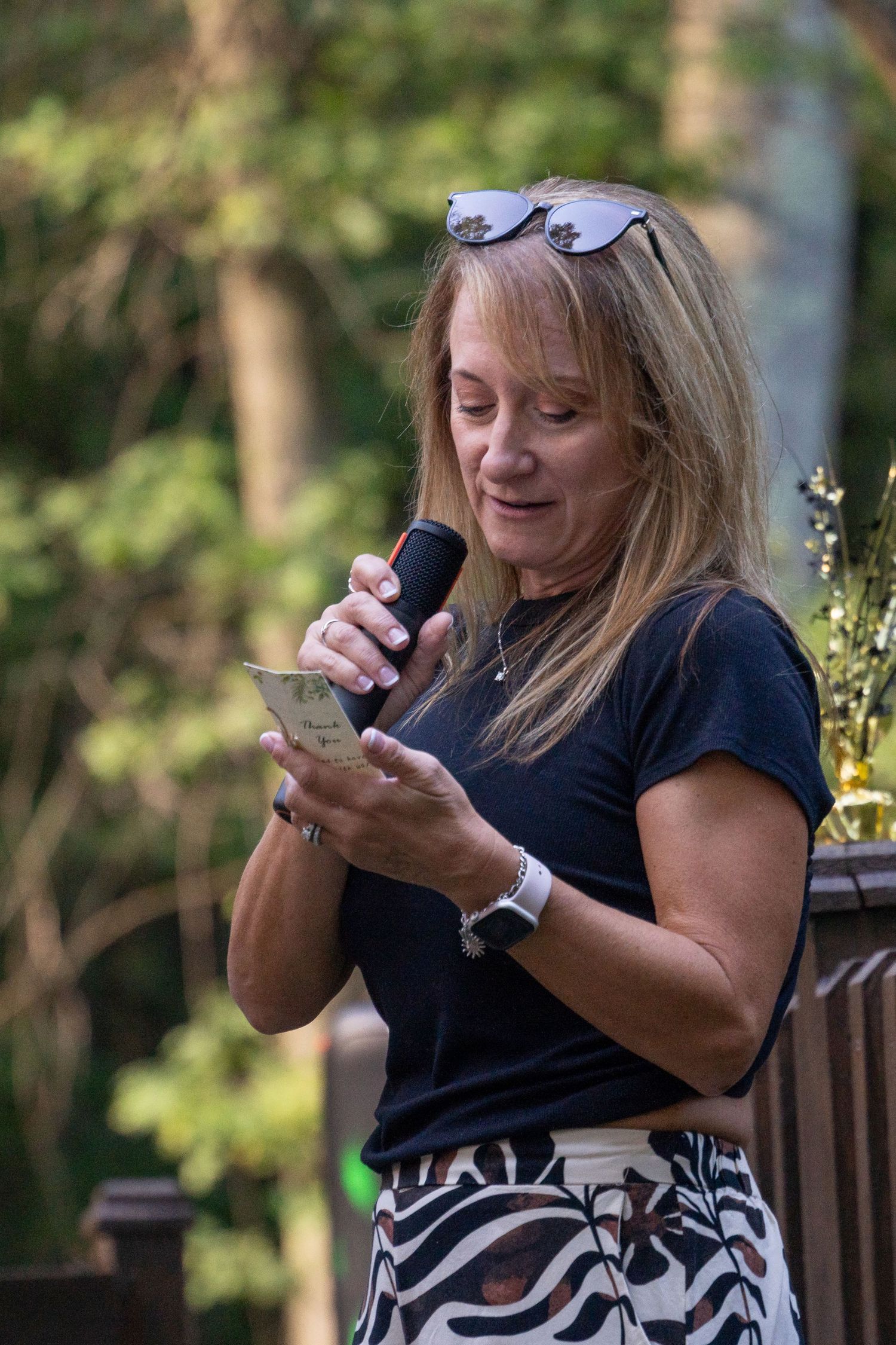 Woman in black shirt using mobile phone while sitting outdoors.
