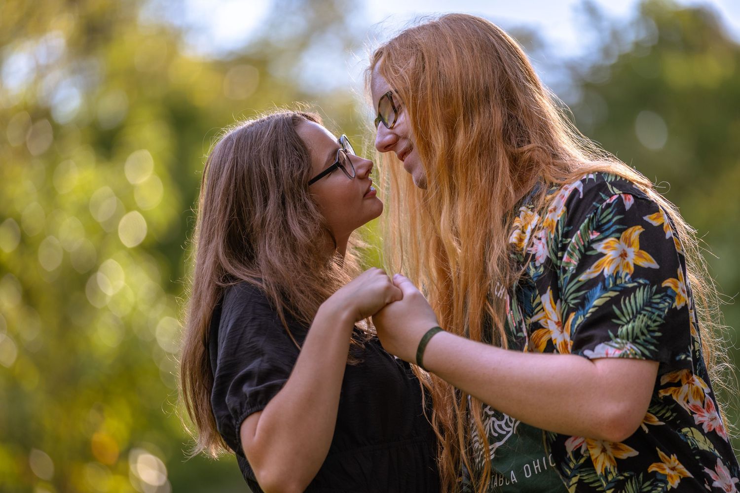 A candid moment captured between two people in a sunny outdoor setting.