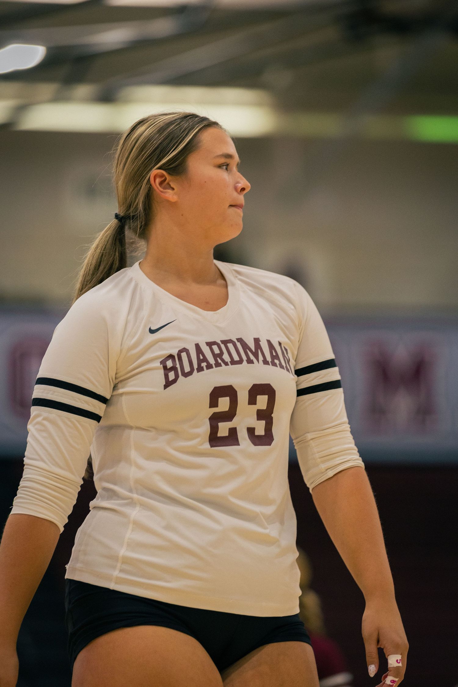 Volleyball player in white Boardman jersey number 23 prepares for match.