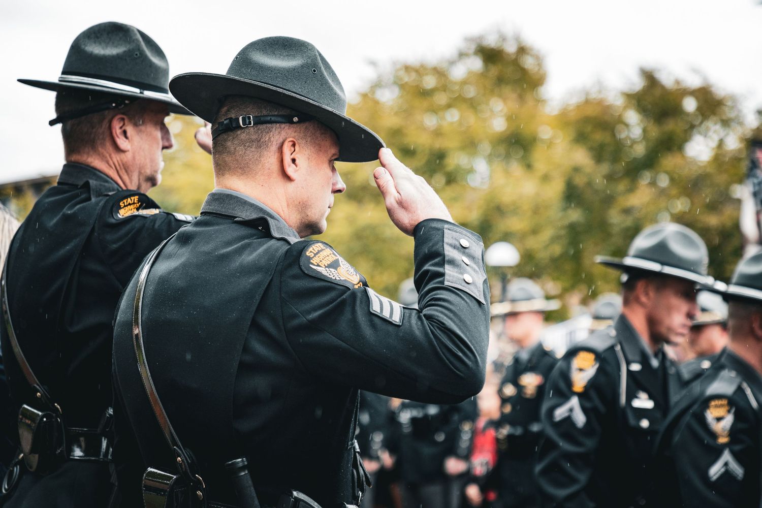 Police officers in dress uniforms and campaign hats stand at attention during a ceremony.