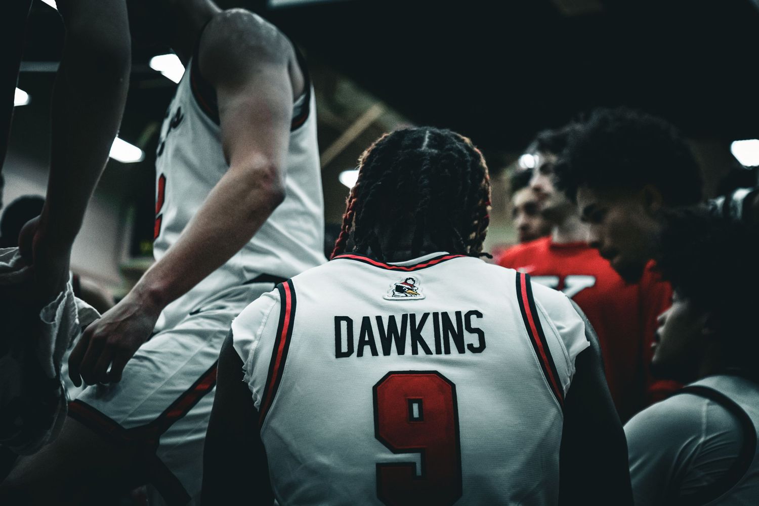 Basketball players in white jerseys compete during an indoor game.