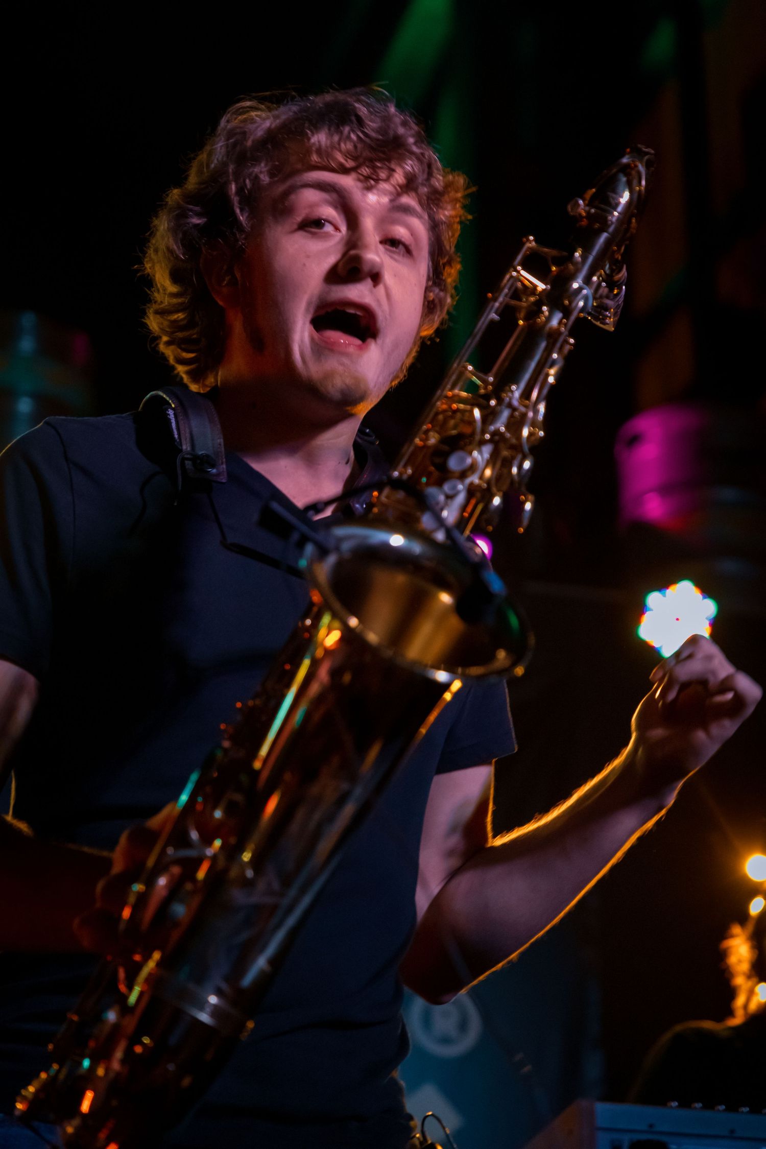 Musician performing passionately with saxophone under dramatic stage lighting.