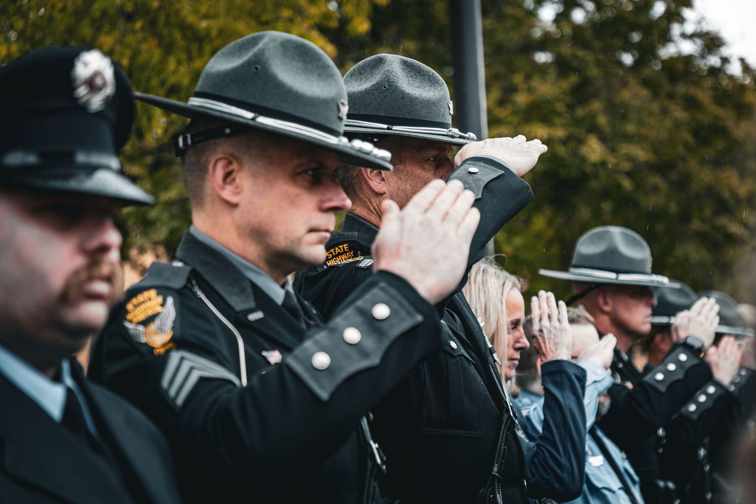 Officers in formal dress uniforms salute during an official ceremony.