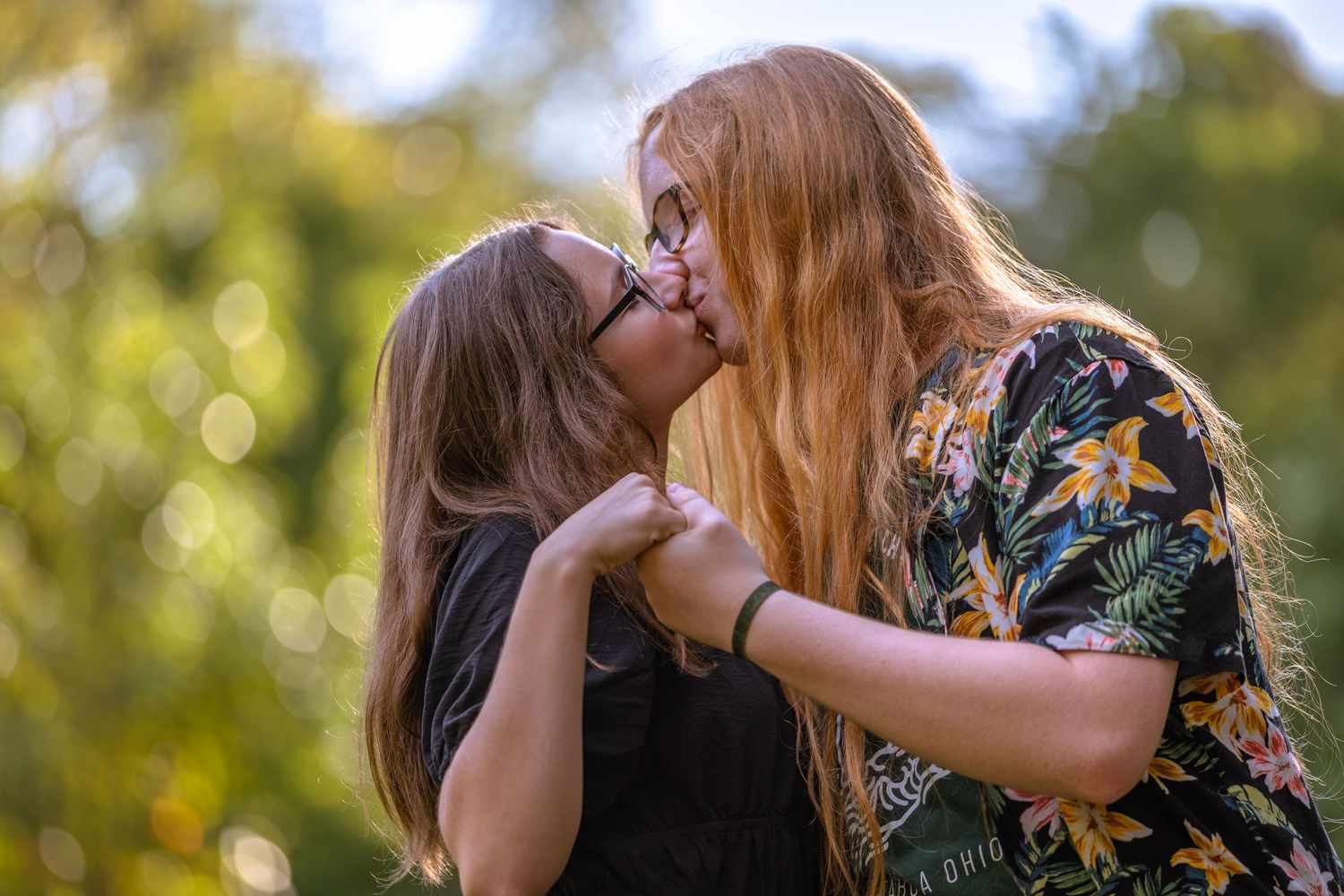 Two people share a tender moment in a park with warm autumn lighting.