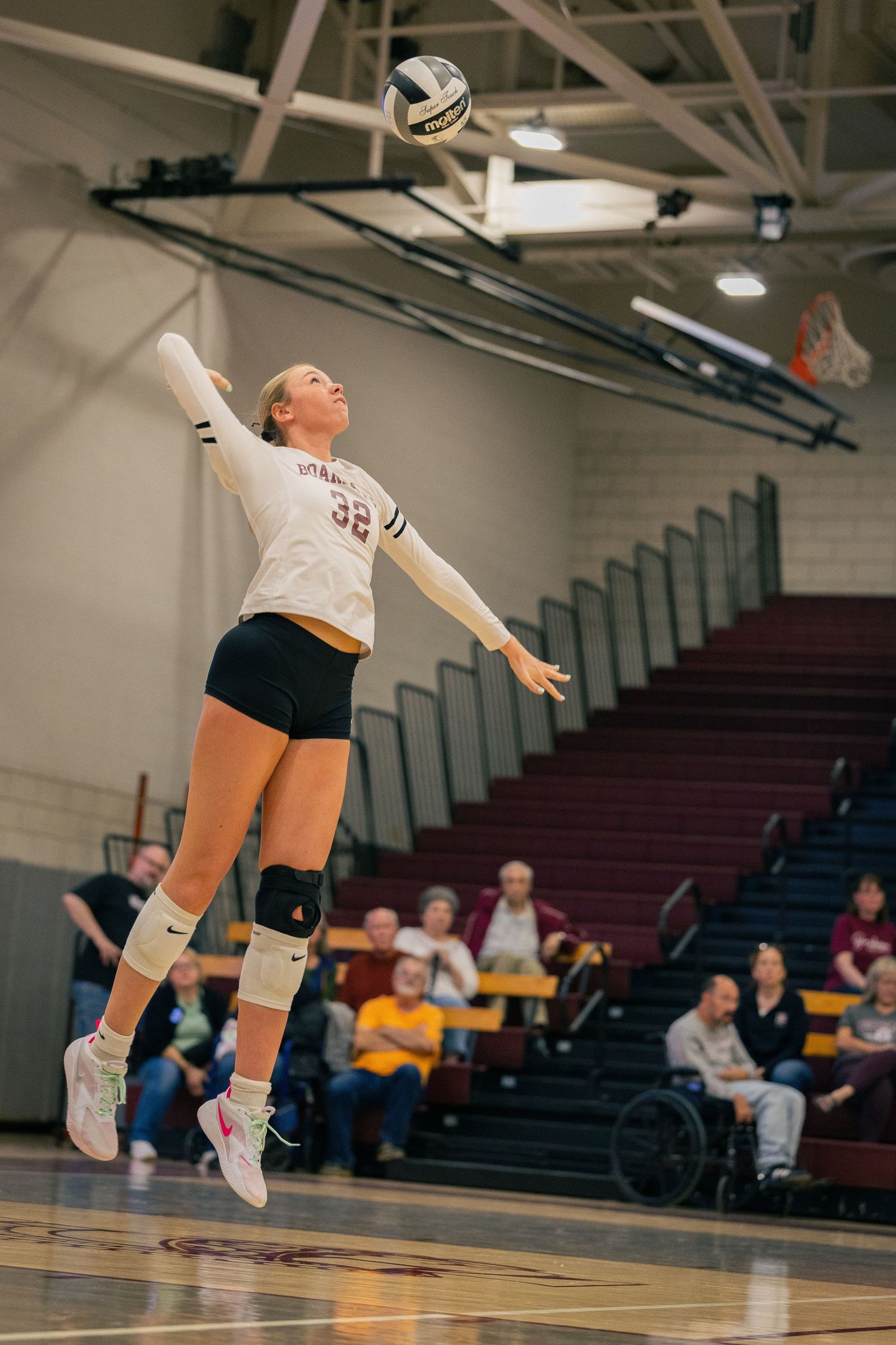 Volleyball player diving for ball during indoor match.