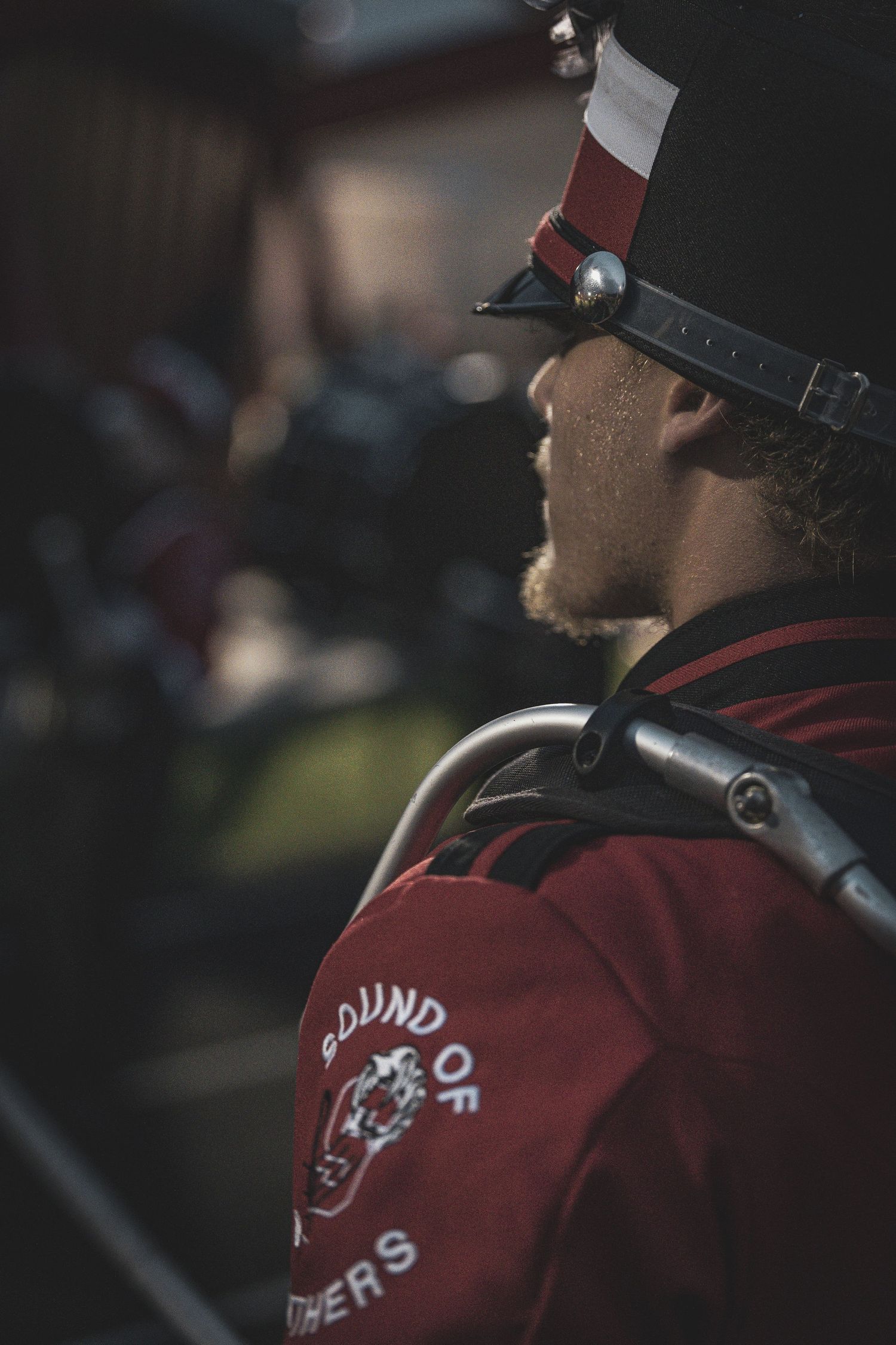 Marching band drummers in red and black uniforms perform during a field show.