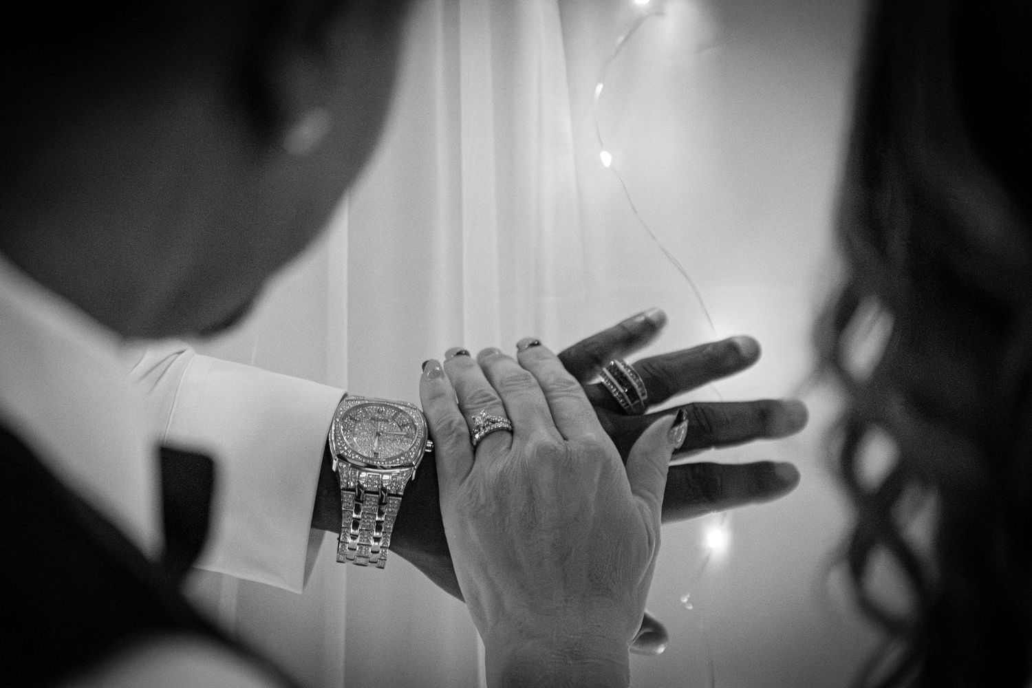 Black and white close-up of hand with luxury watch and rings.