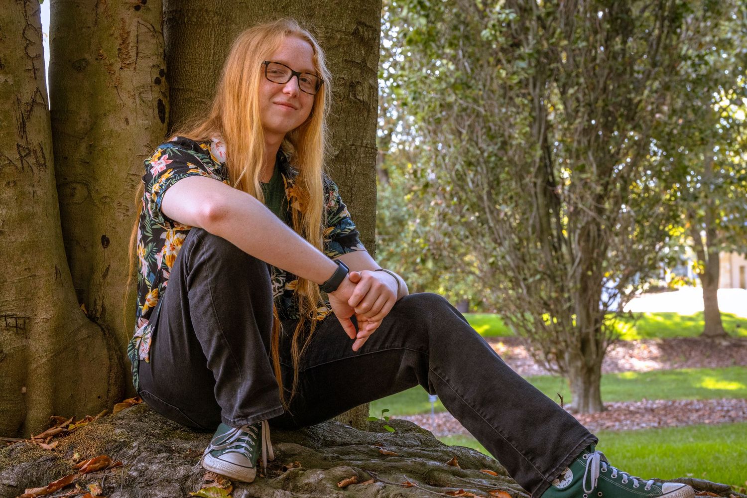 Person resting against tree trunk in natural outdoor setting.