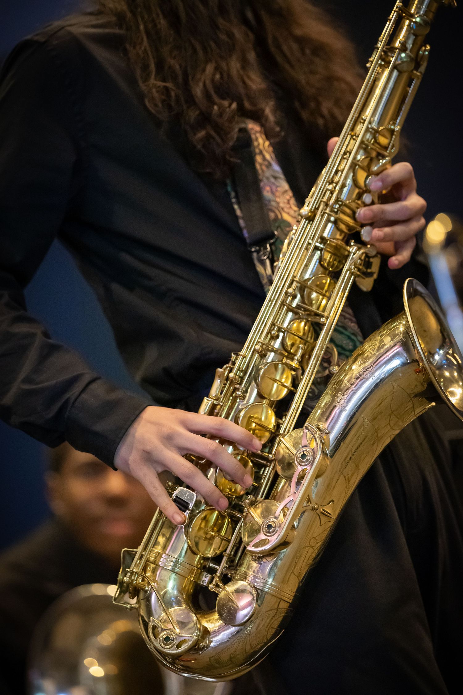 Close-up of a musician playing a shiny gold saxophone during a jazz performance.
