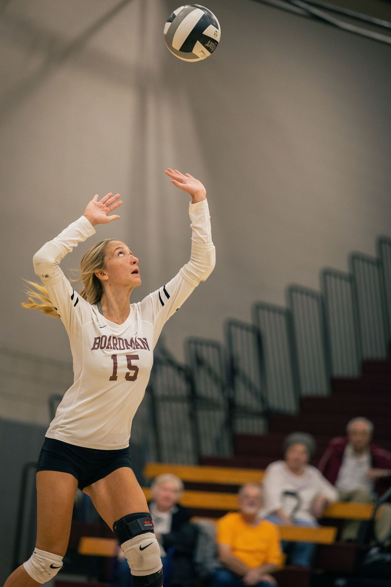Volleyball player leaps to hit ball during intense indoor match.